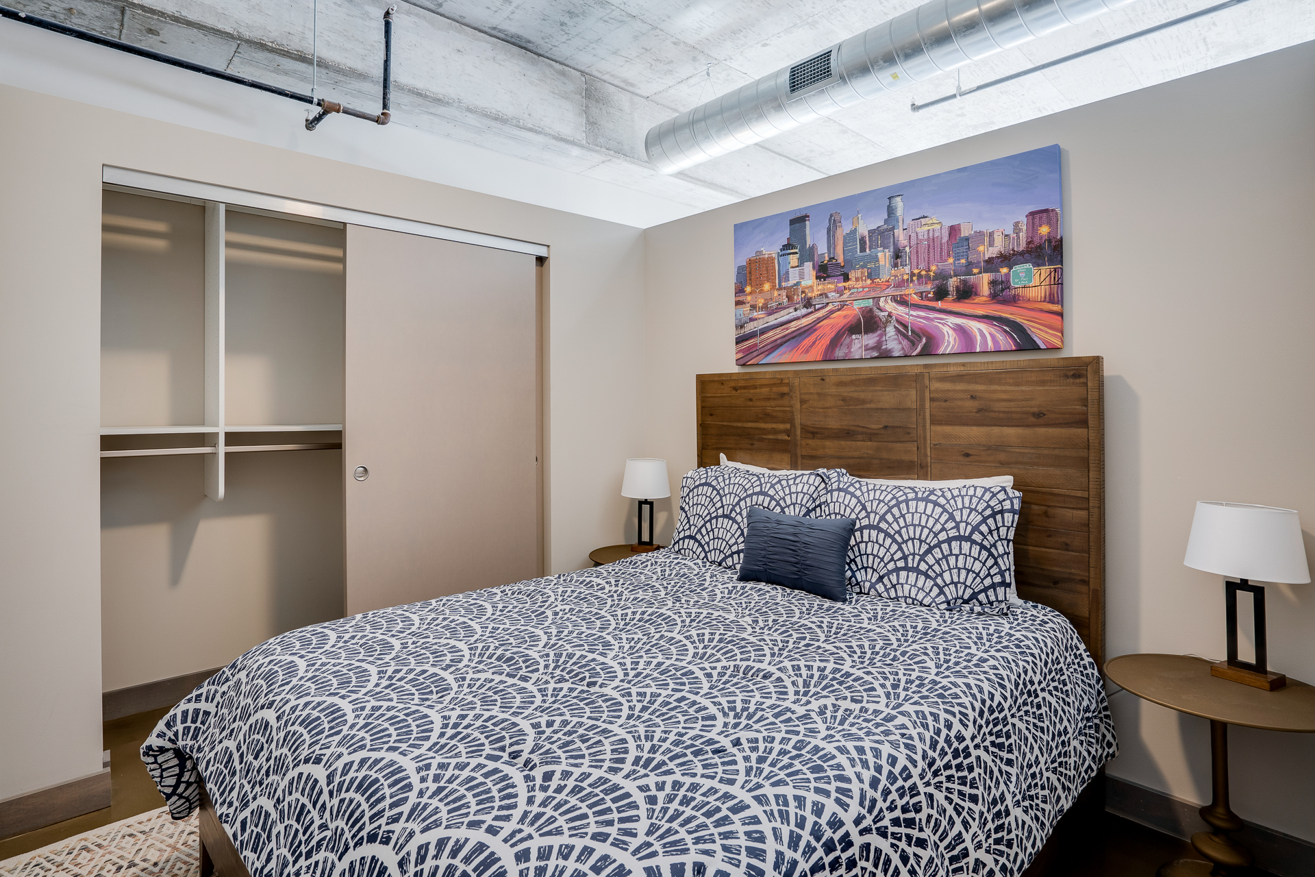 A modern bedroom with a stylish bed and city skyline artwork.