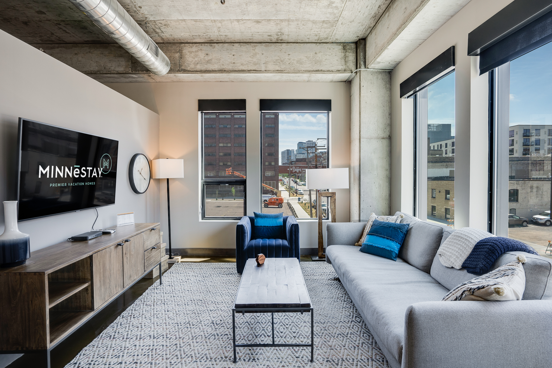 Contemporary living room featuring a gray sectional sofa, black coffee table, and large windows with an urban view.