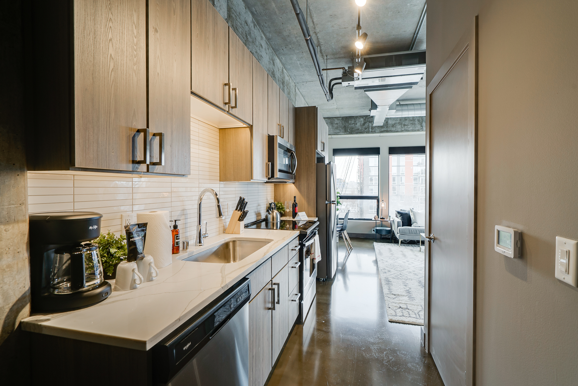 Modern kitchen with wooden cabinets and stainless steel appliances in an open apartment.