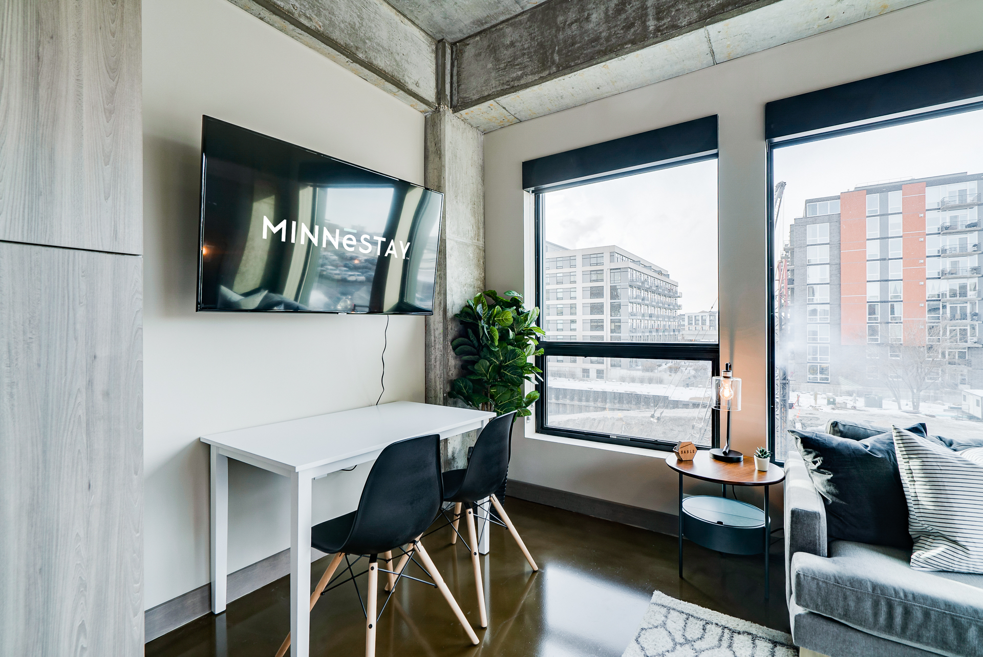 A modern living space featuring a sleek television, minimalist furniture, and urban views.