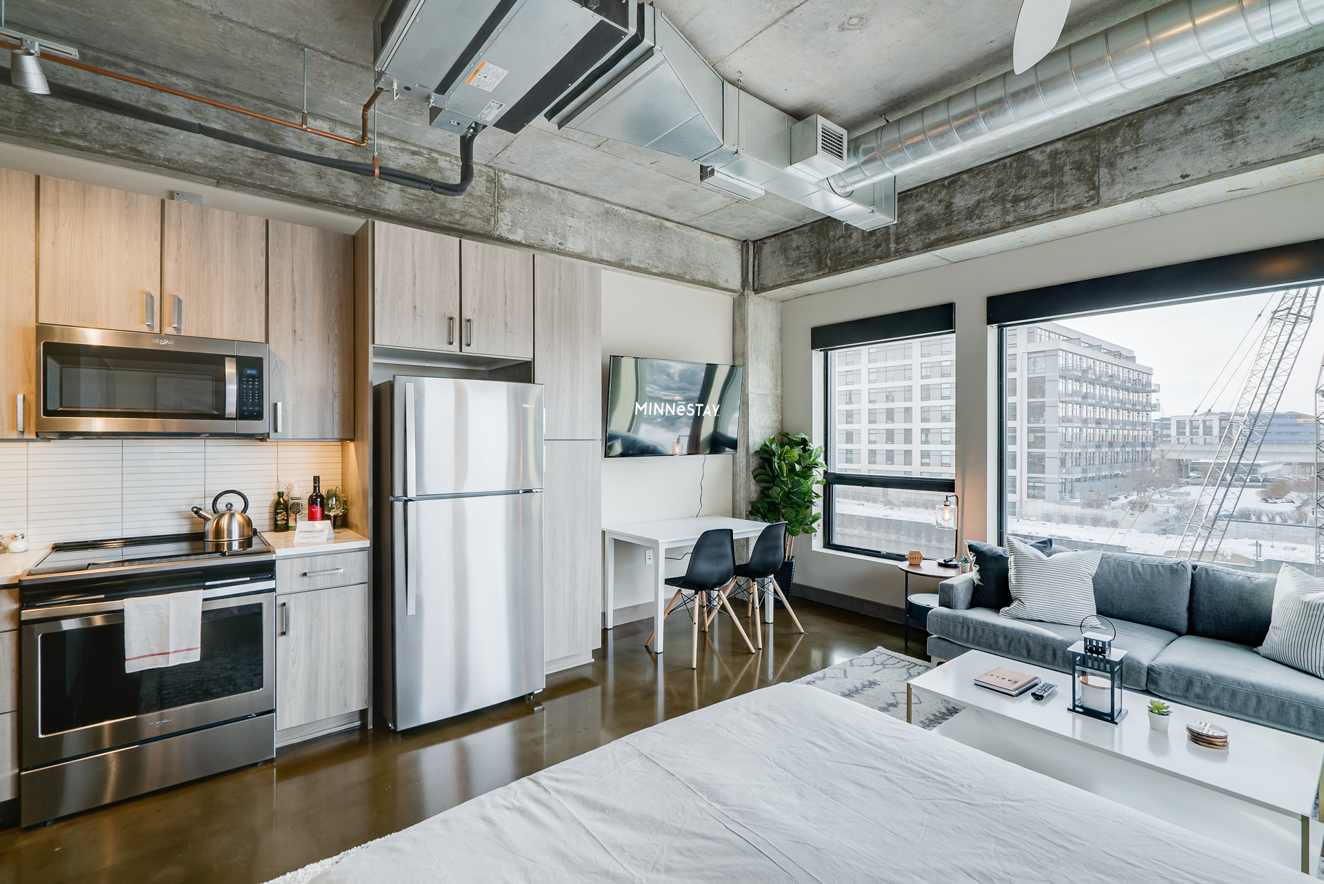 A modern studio apartment featuring an industrial design with stainless steel appliances and stylish furnishings.