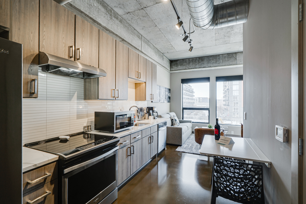A sleek, modern kitchen featuring light wood cabinetry and stainless steel appliances.