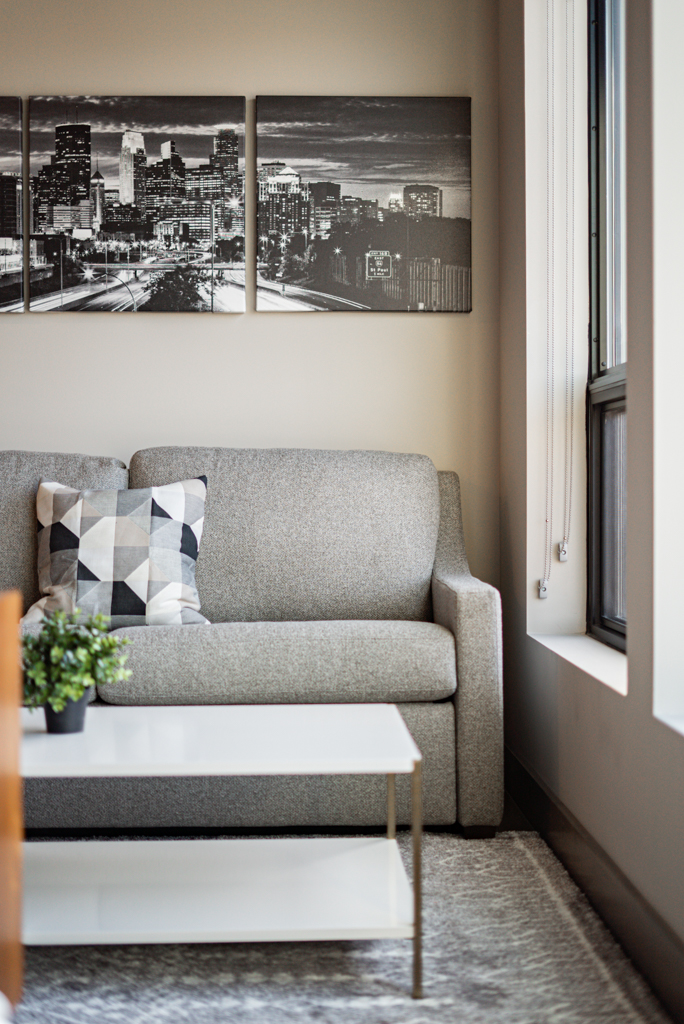 A modern living room with a cozy sofa and cityscape artwork.