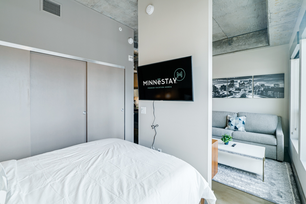 A stylish and modern studio apartment featuring a cozy bed and inviting sitting area.