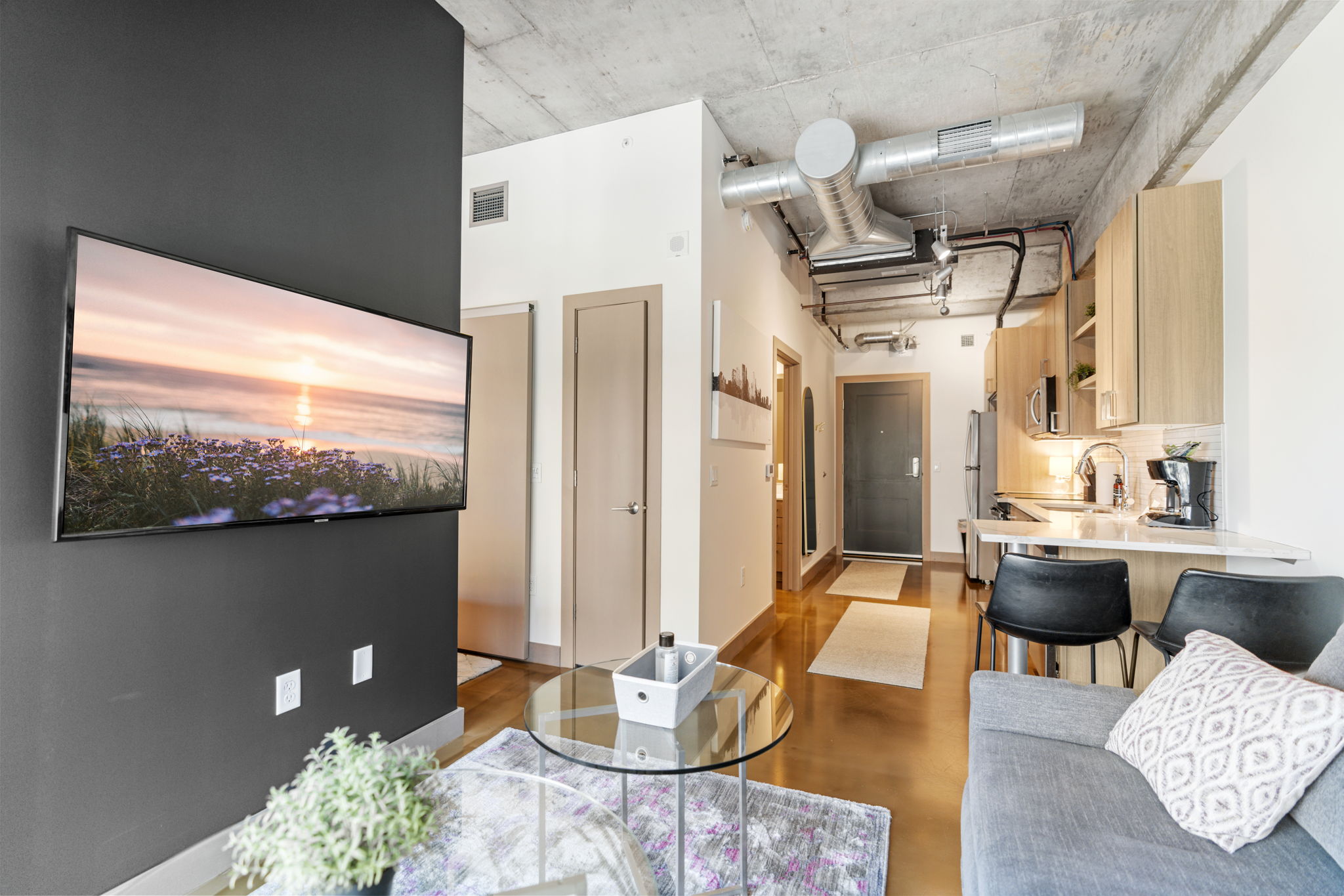 A modern apartment interior featuring a living area and kitchen space.