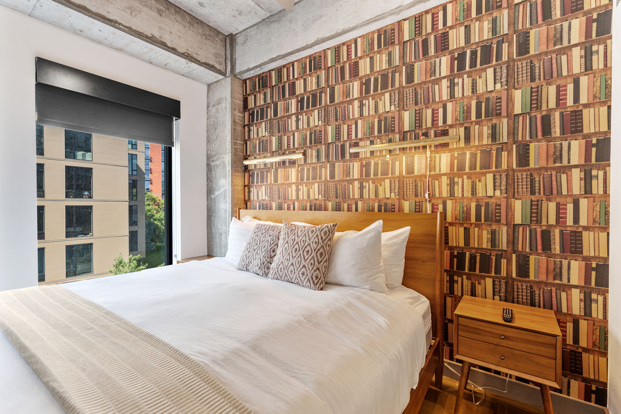A cozy modern bedroom with a bookshelf wallpaper and a warm ambiance.