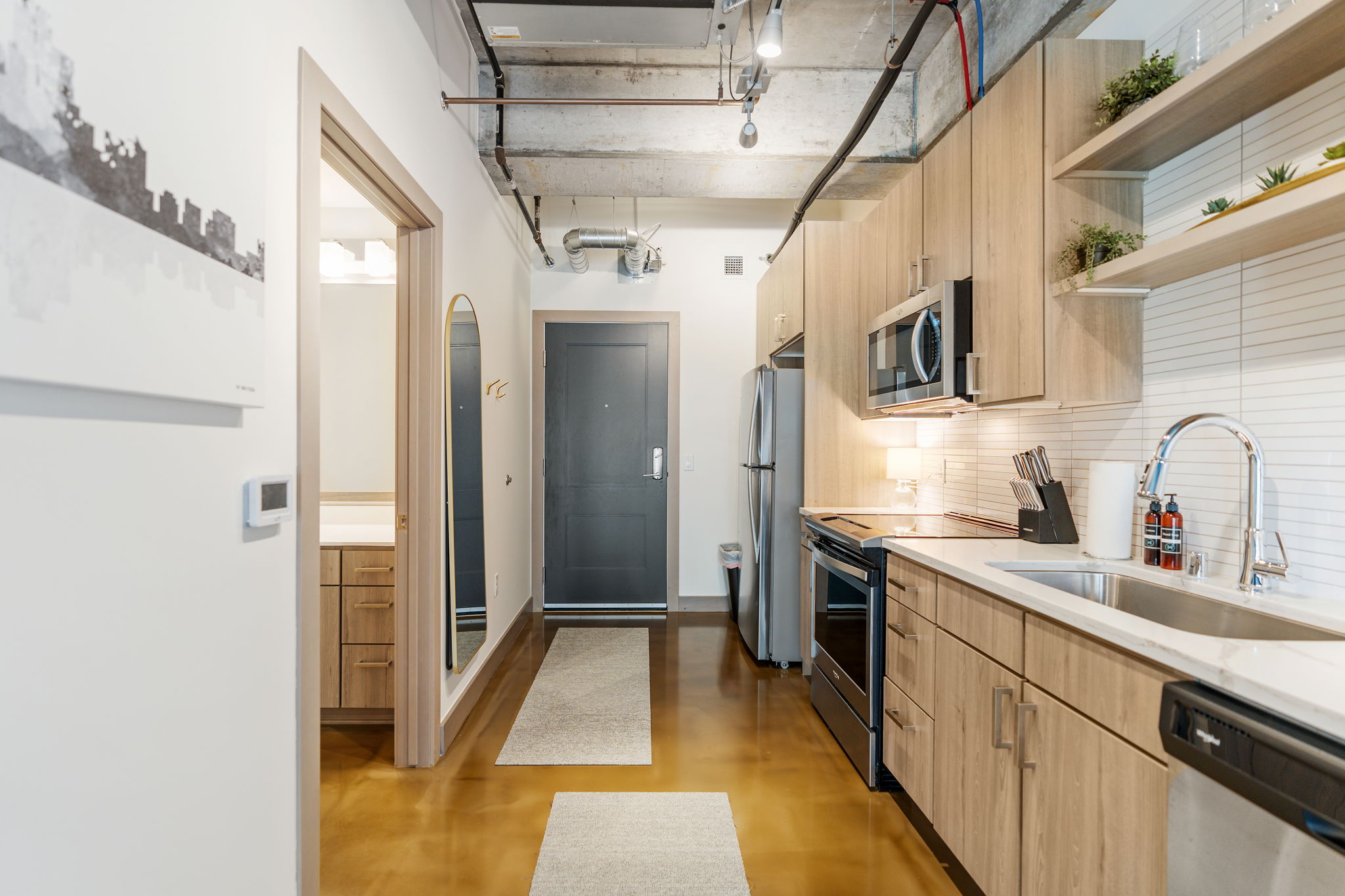 A modern kitchen and entryway featuring sleek design and industrial elements.
