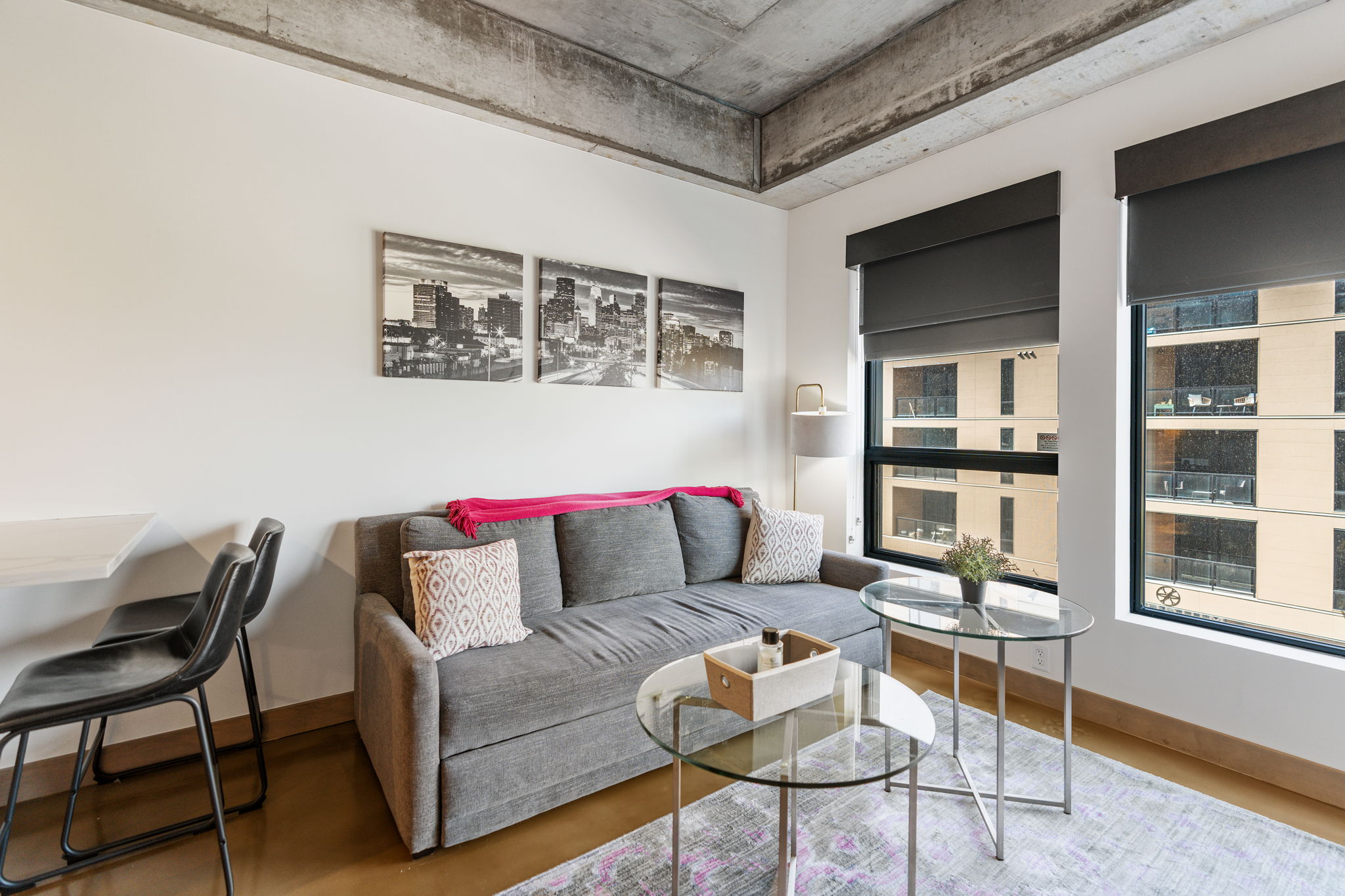 A stylish and modern living space with a gray sofa and city skyline artwork.