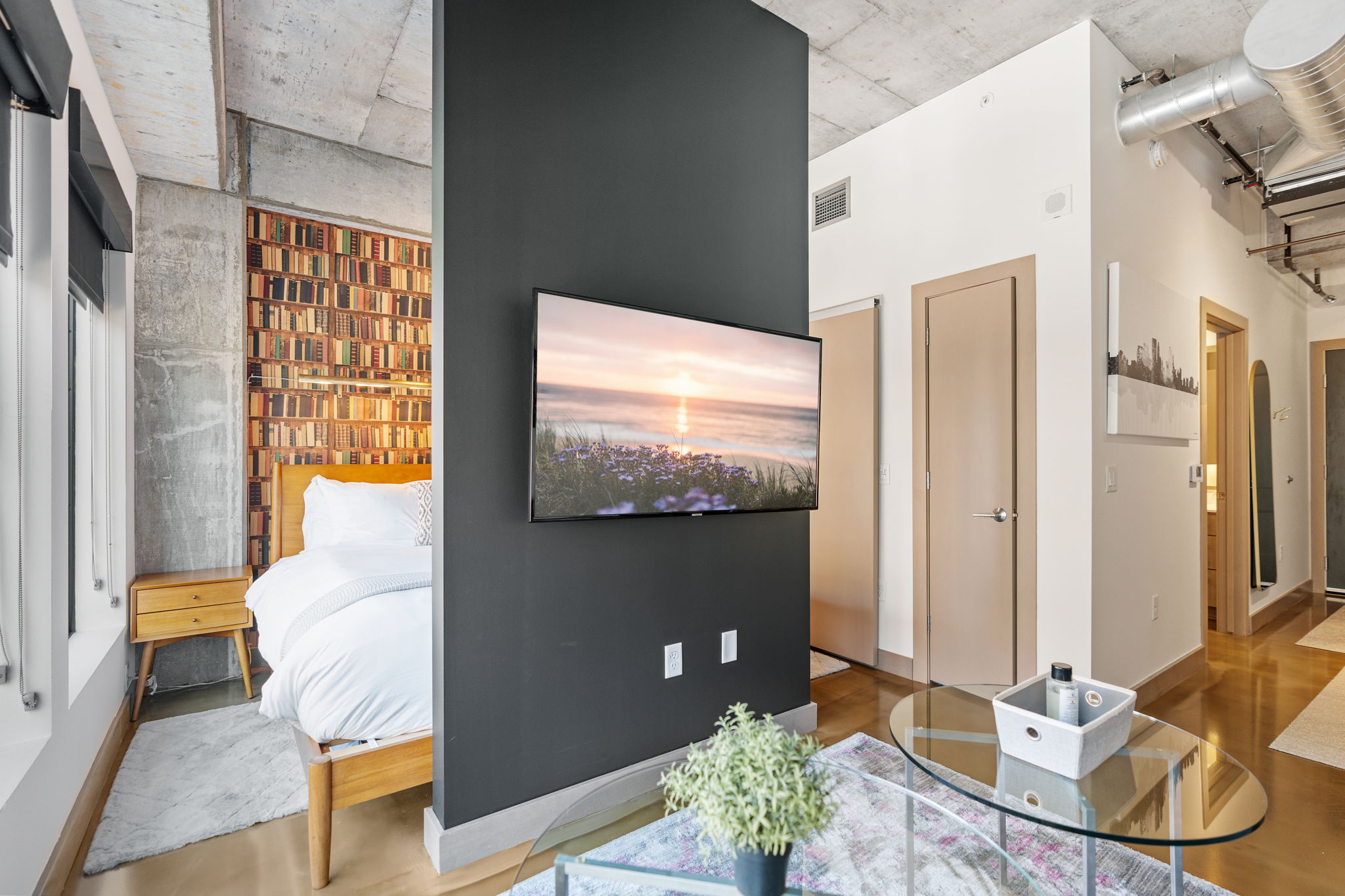 A modern studio with a cozy atmosphere, featuring a stylish bed and a vibrant bookshelf wall.