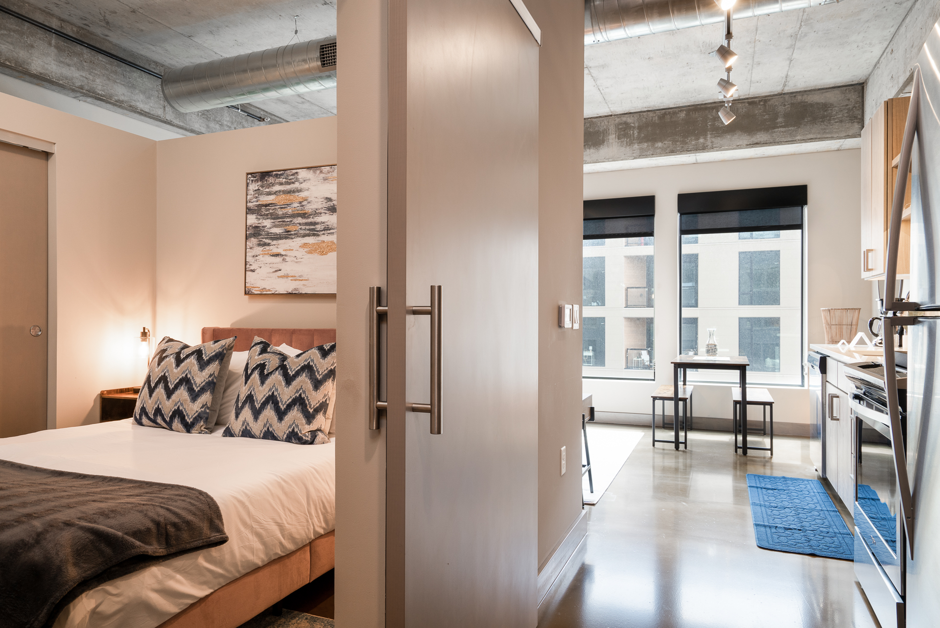A modern open studio apartment featuring a cozy bedroom and compact kitchen.