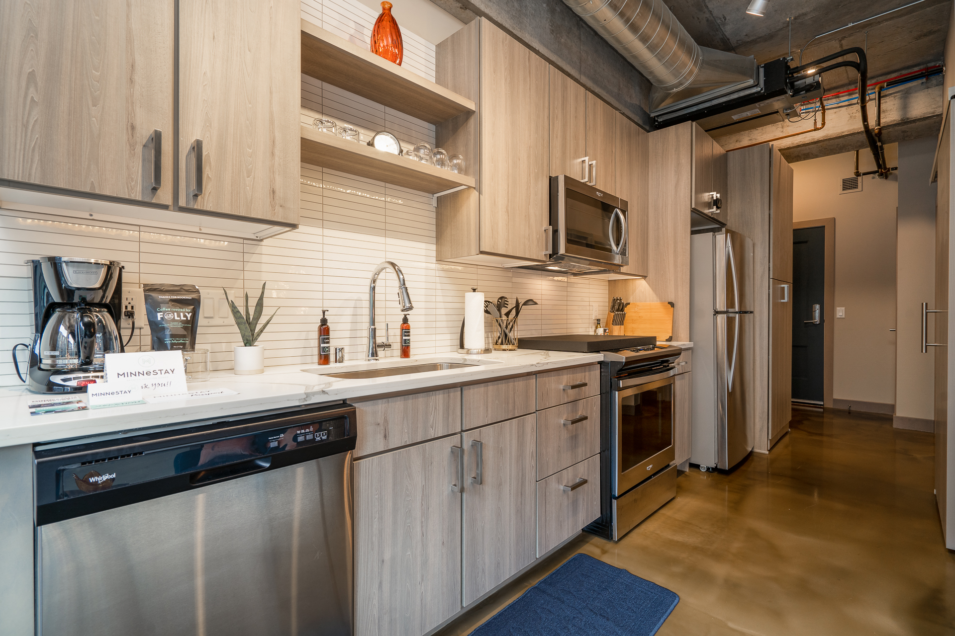 A modern kitchen design with light wooden cabinetry and stainless steel appliances.