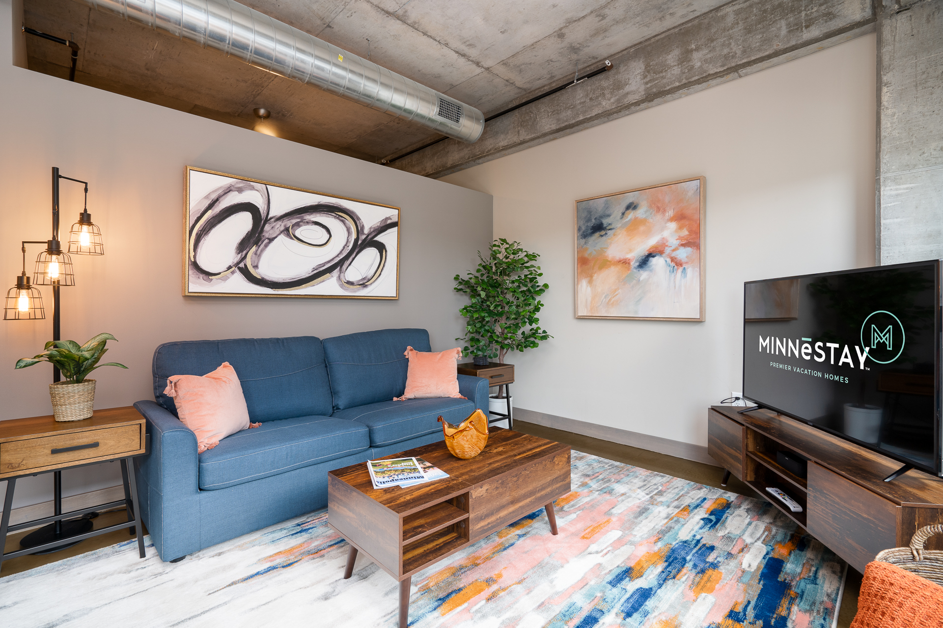A cozy and modern living room featuring a blue sofa, abstract art, and stylish decor.