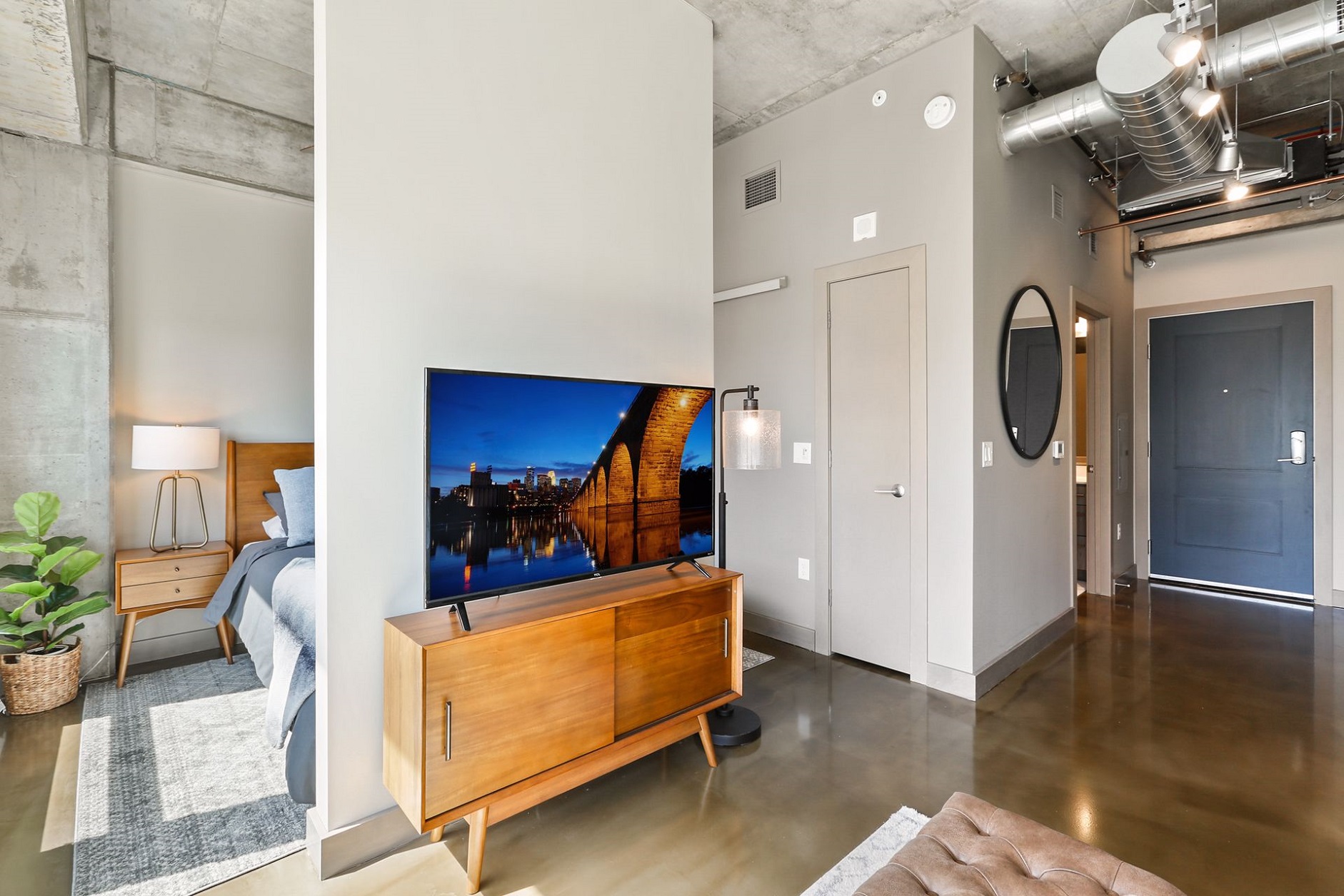 A modern studio apartment with an industrial design featuring polished concrete floors and stylish decor.