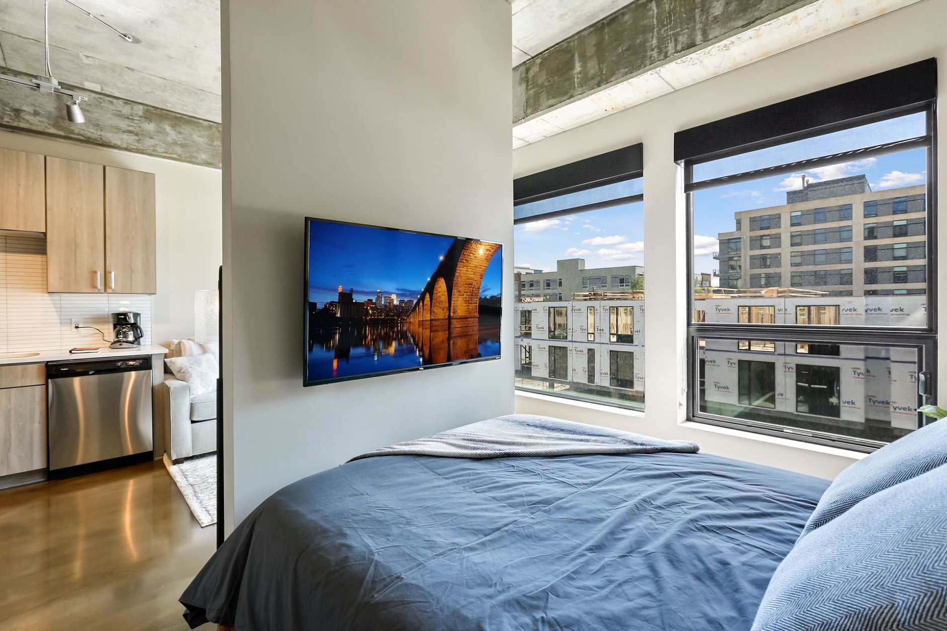 Modern studio apartment with vibrant city view and cozy bedding.