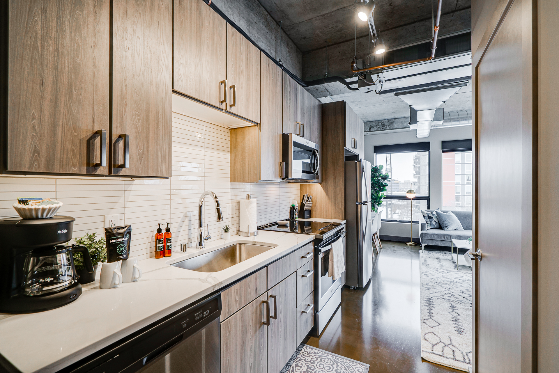 Contemporary kitchen with dark wood cabinets and stainless steel appliances in an apartment setting.