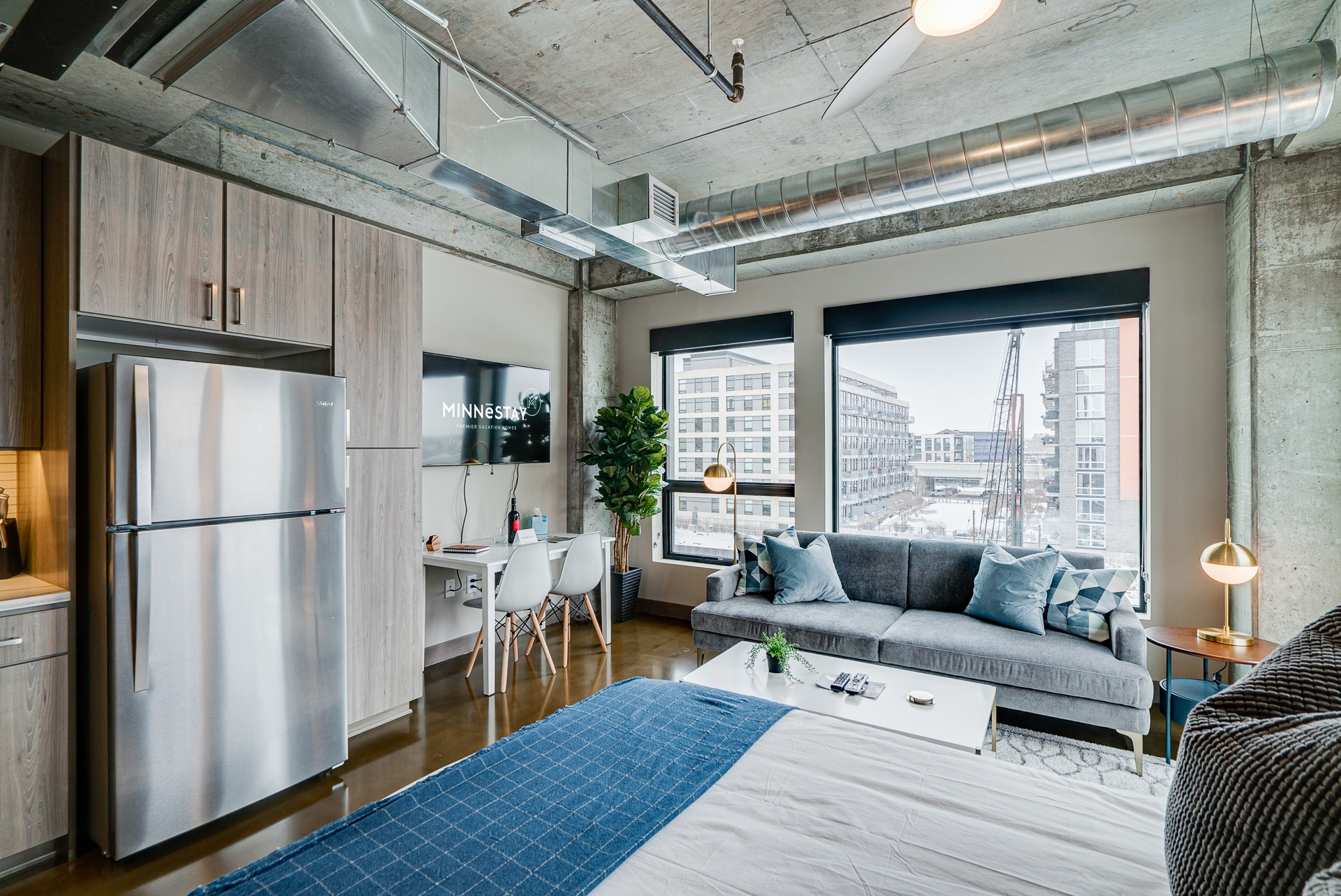 A cozy, modern studio apartment with industrial elements and city views.