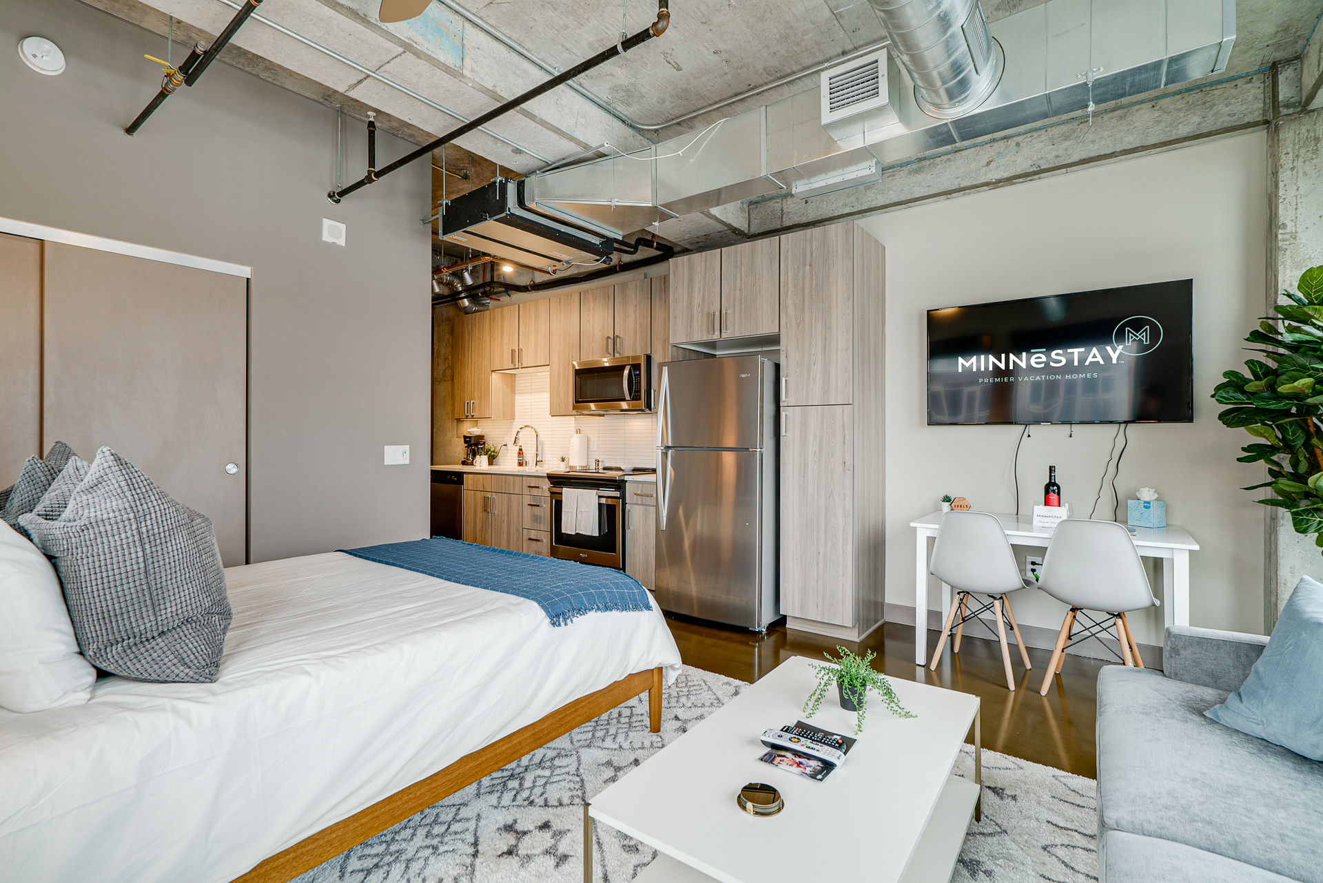 A stylish studio apartment featuring a comfortable sleeping area and a modern kitchenette.