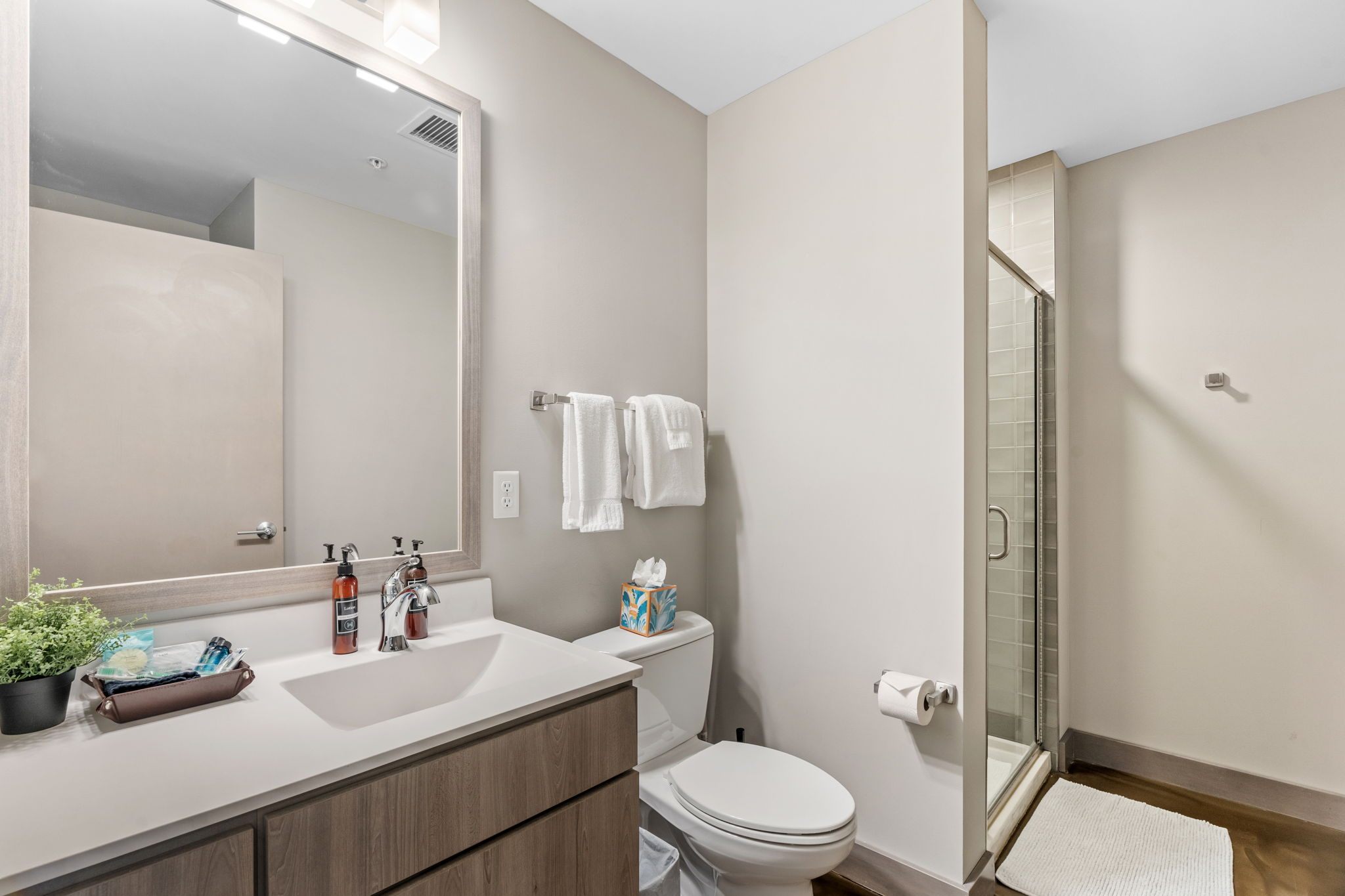 A modern and elegantly designed bathroom with a sleek double sink and a glass shower.