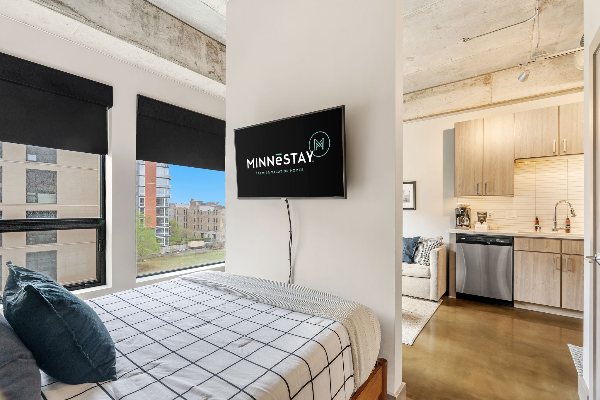A modern studio apartment designed for comfort and style, featuring a bed, kitchen, and urban views.