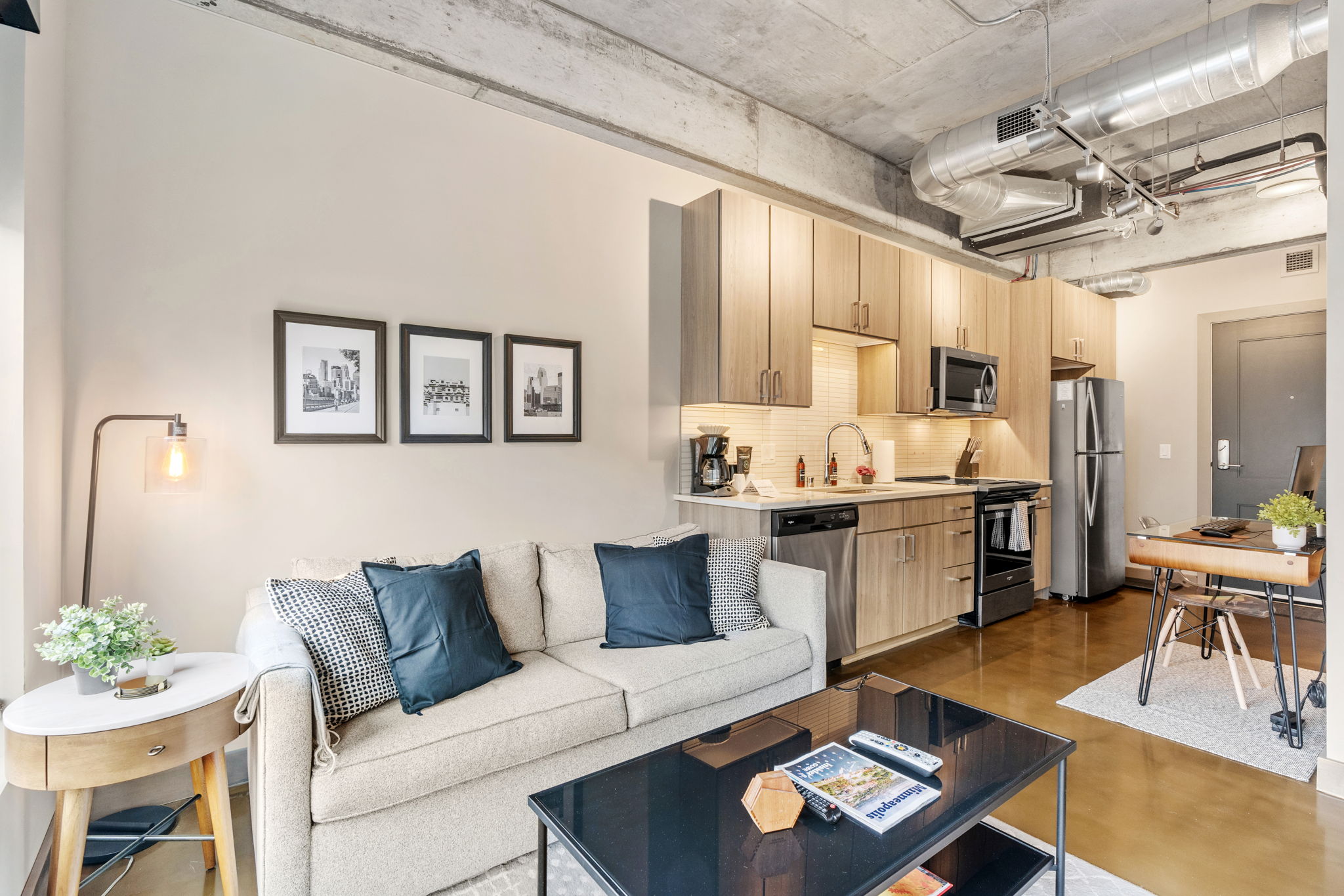 A contemporary studio apartment featuring a living area with a sofa and a kitchen with modern appliances.