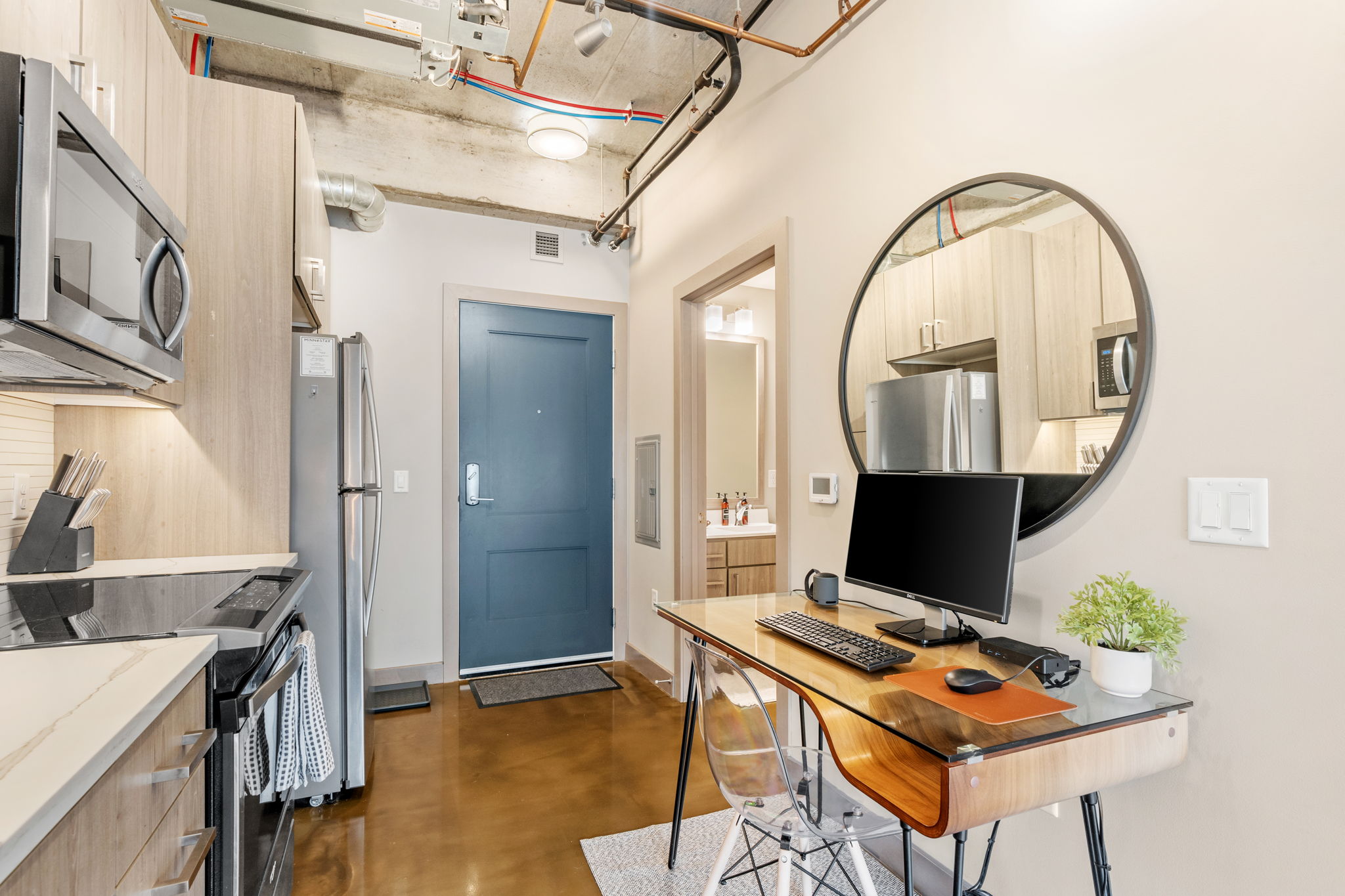 A stylish modern studio apartment featuring a functional workspace and kitchen area.