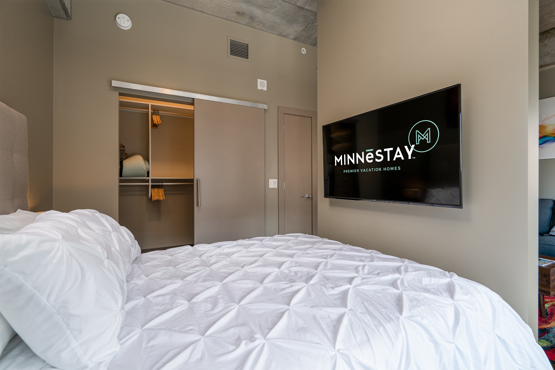 A modern bedroom featuring a stylish bed and a mounted TV.