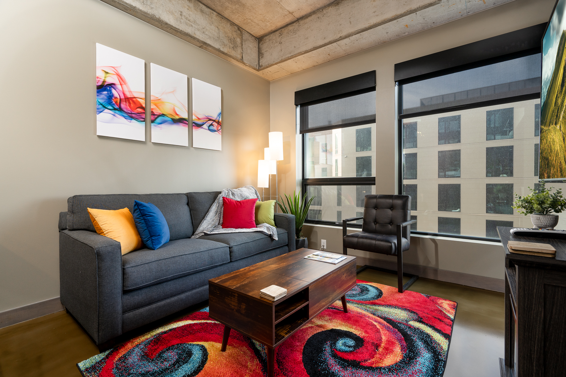Stylish living room with a gray sofa, colorful cushions, and abstract art on the wall.