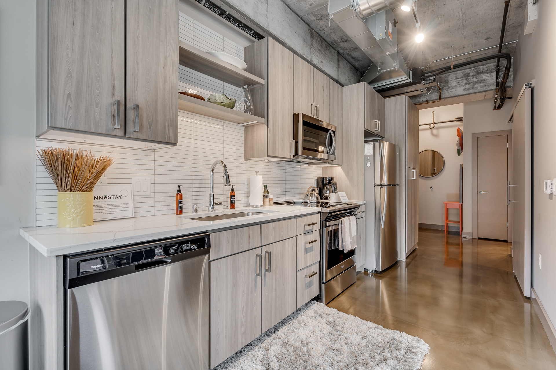 A modern kitchen featuring light wood cabinetry and stainless steel appliances.