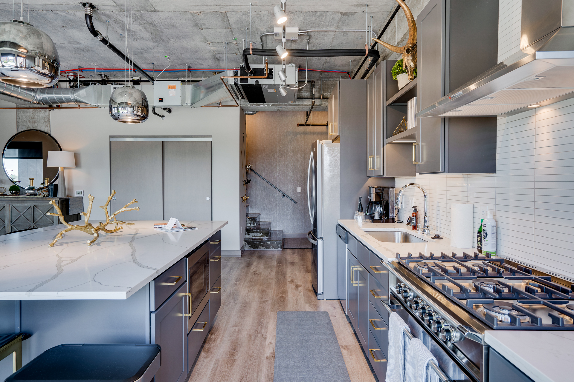 A sleek, modern kitchen with an industrial aesthetic, featuring a marble island and stainless steel appliances.