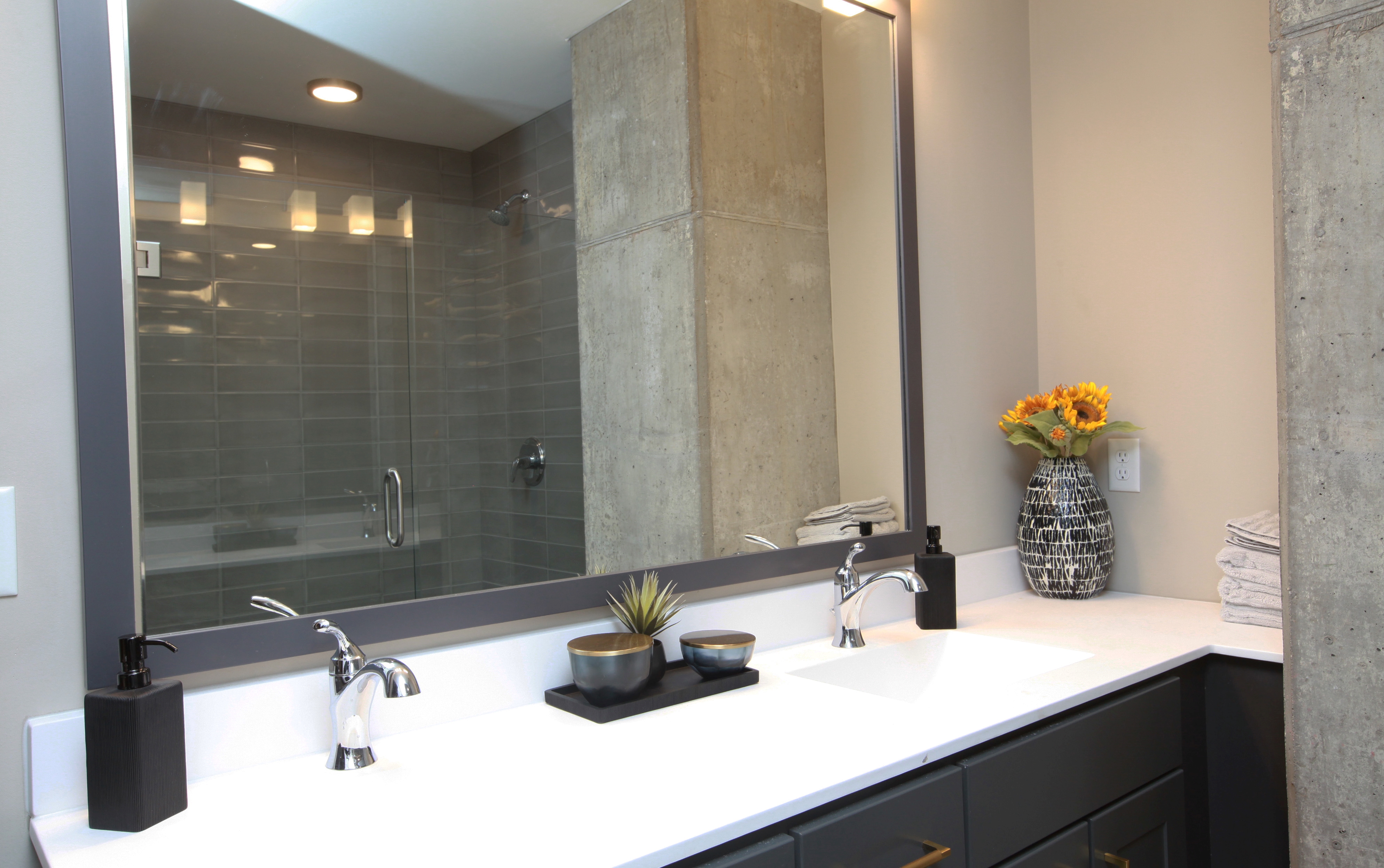 A modern bathroom with a sleek vanity, stylish decor, and a spacious glass shower.