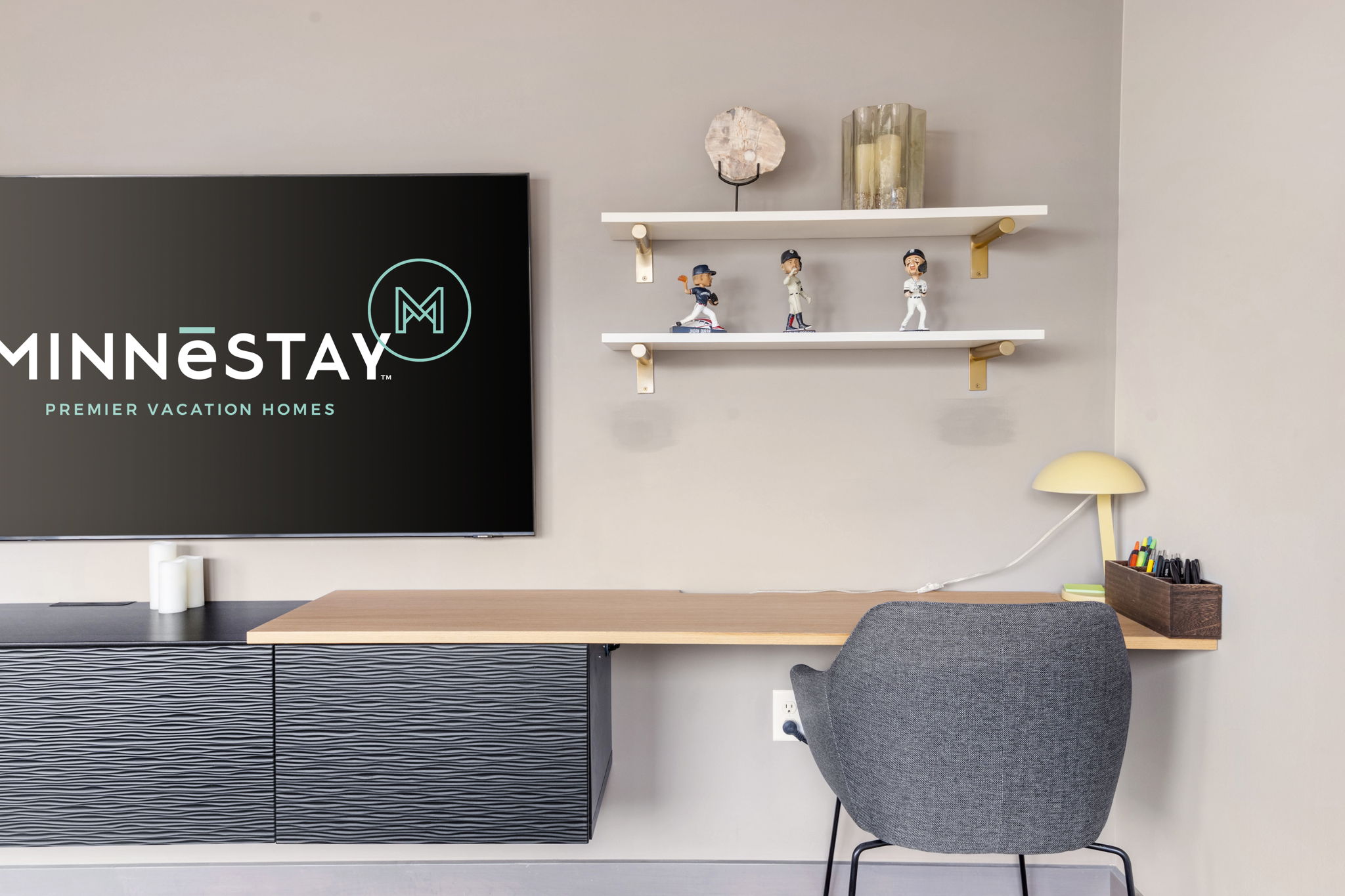 A stylish modern workspace featuring a sleek desk, decorative shelf, and MINNESTAY branding.