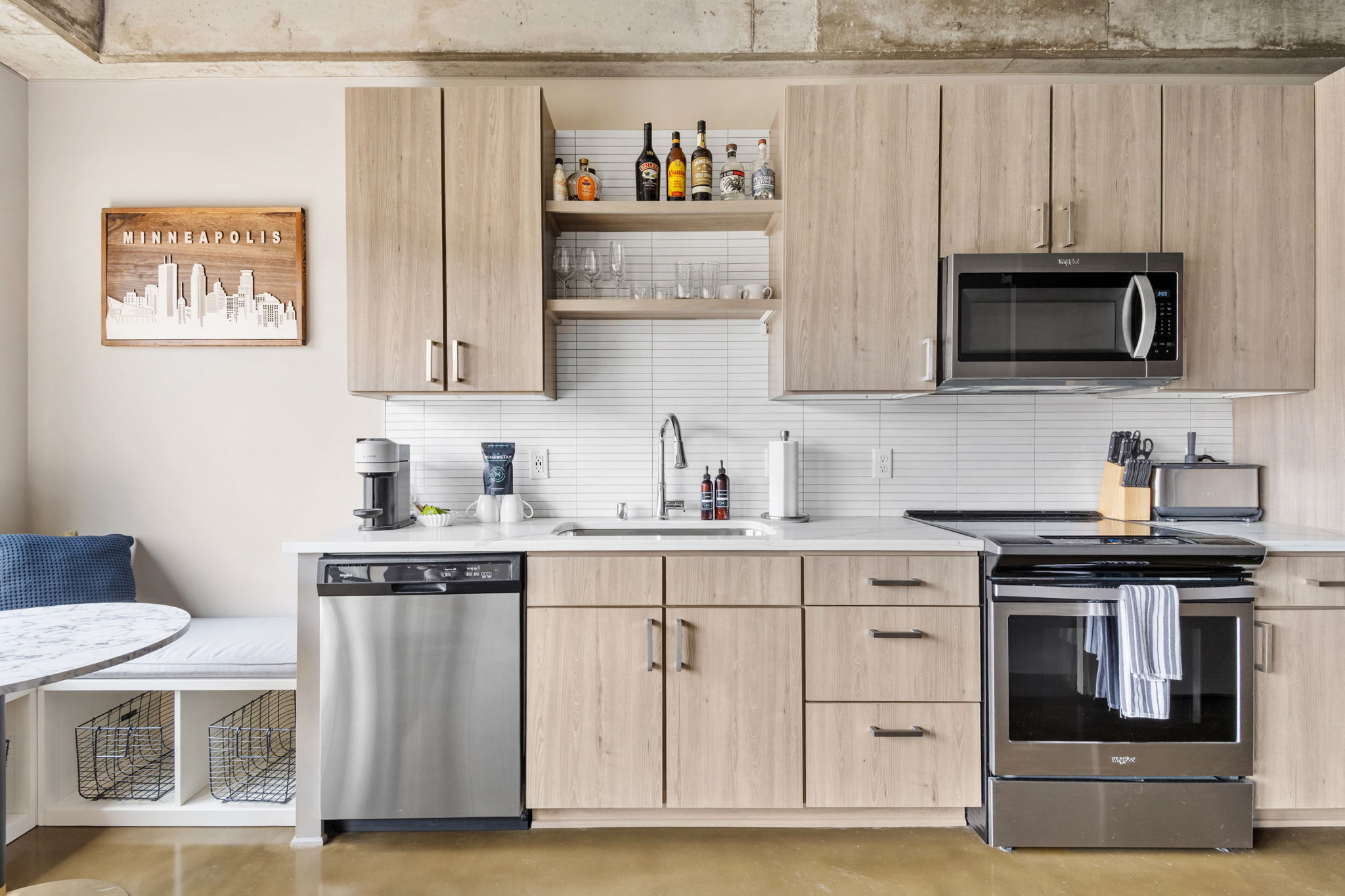 A modern kitchen featuring light wood cabinetry, a minimalist design, and a cozy dining nook.