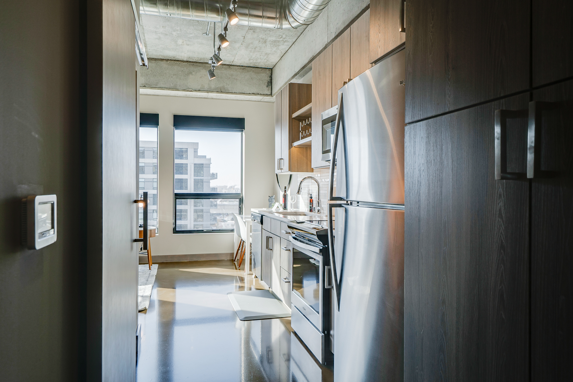 A modern kitchen and living area featuring stainless steel appliances and urban views.