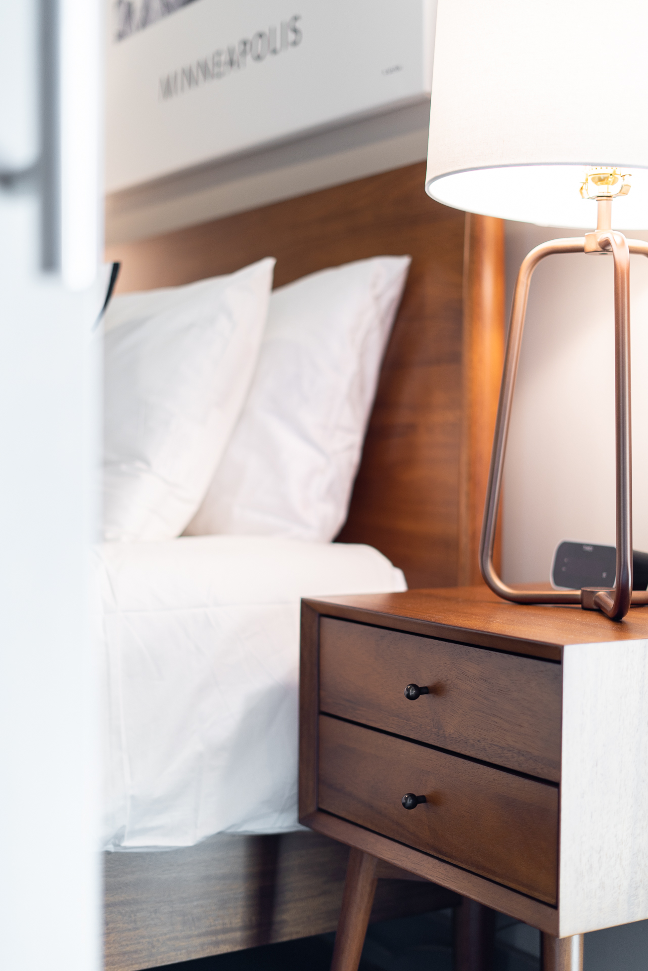 A modern bedroom featuring a stylish bedside table and lamp beside a neatly made bed.
