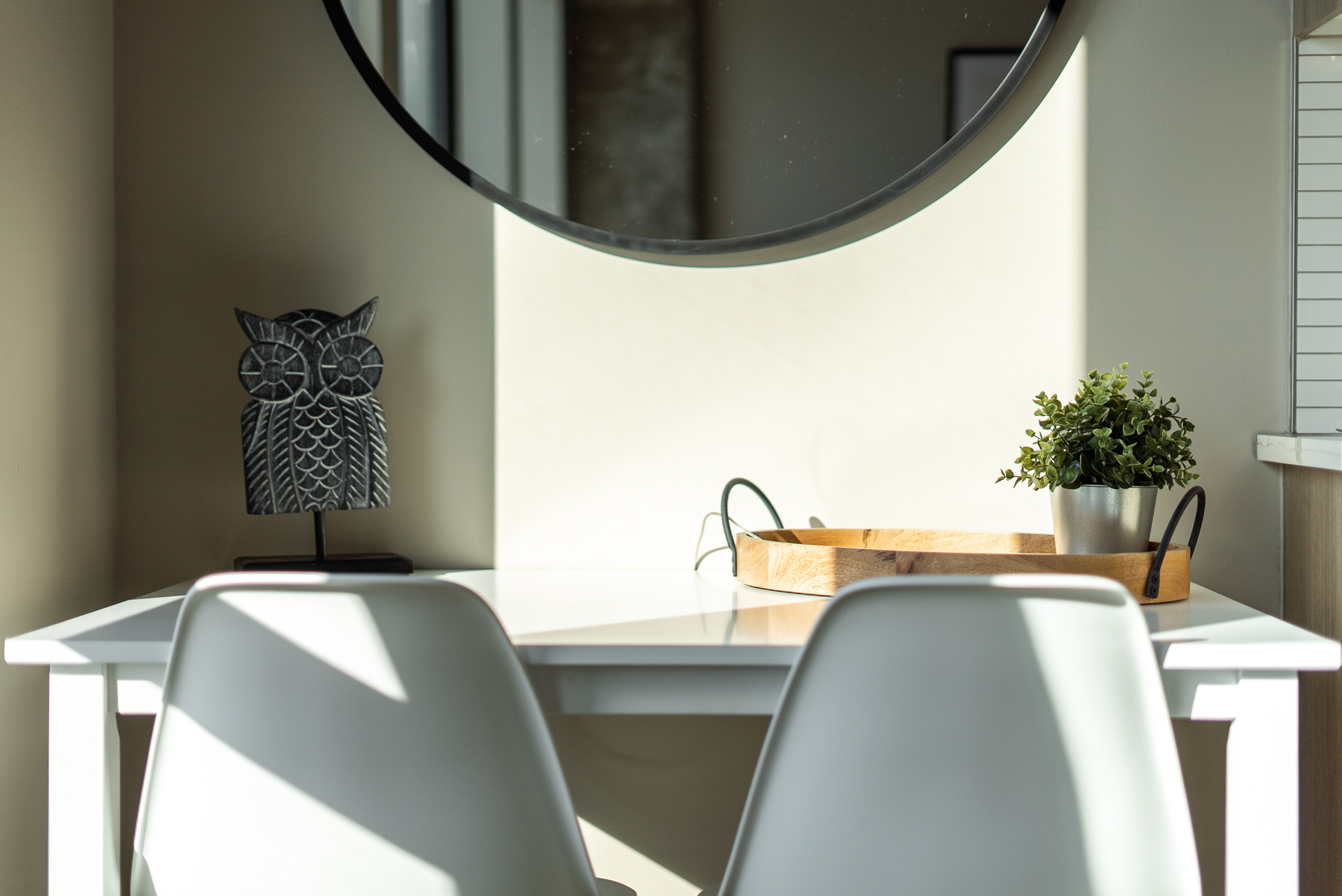 A serene corner with a minimalist table setting and decorative owl.