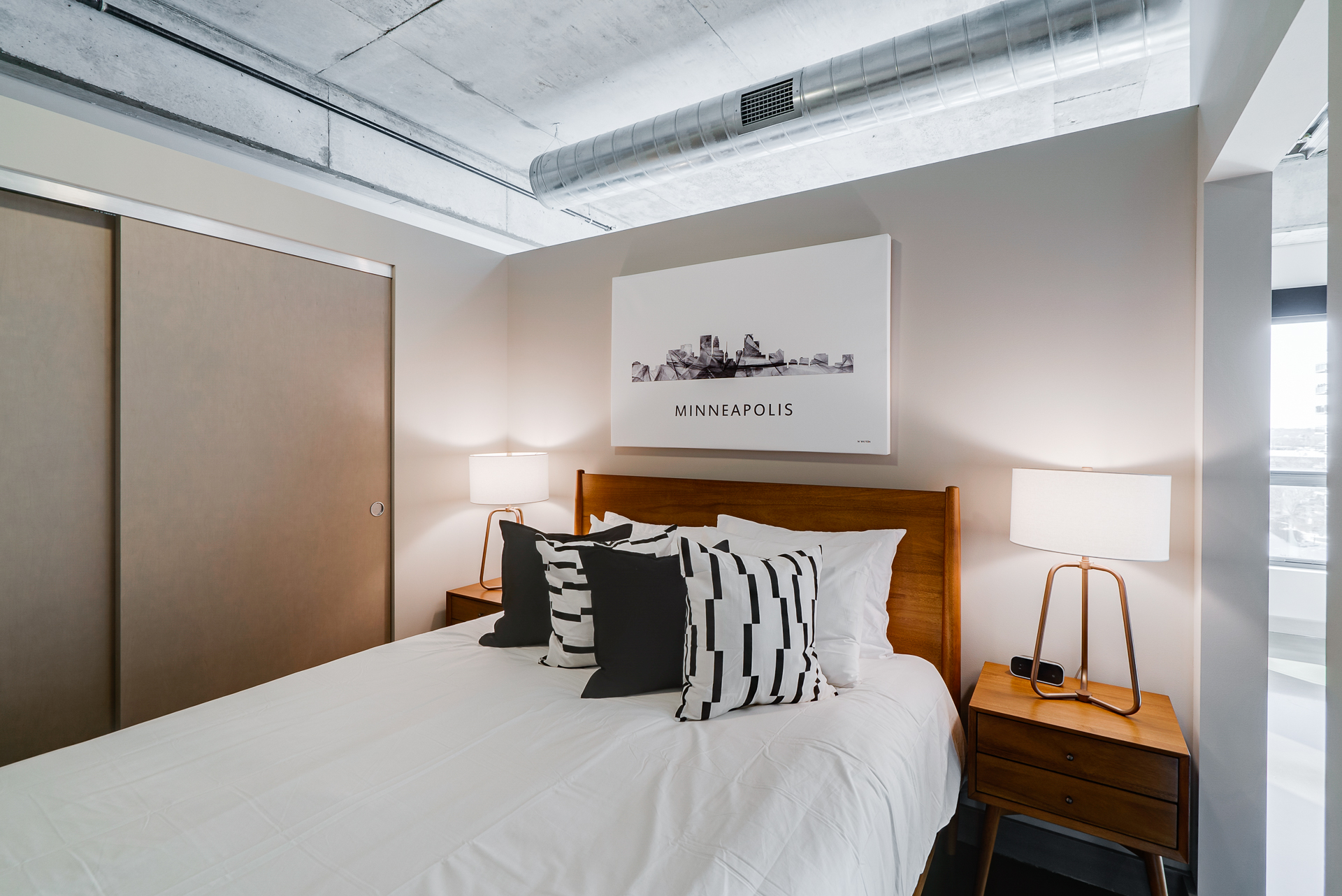 A cozy modern bedroom featuring a minimalist design with a Minneapolis skyline art piece.