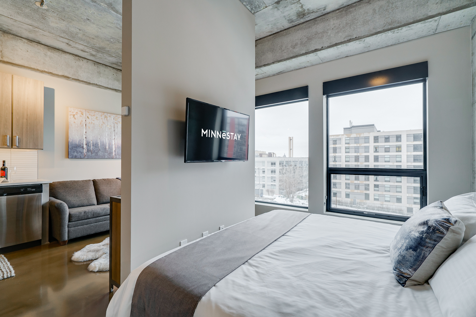 A stylish studio apartment with a cozy bed and modern amenities.