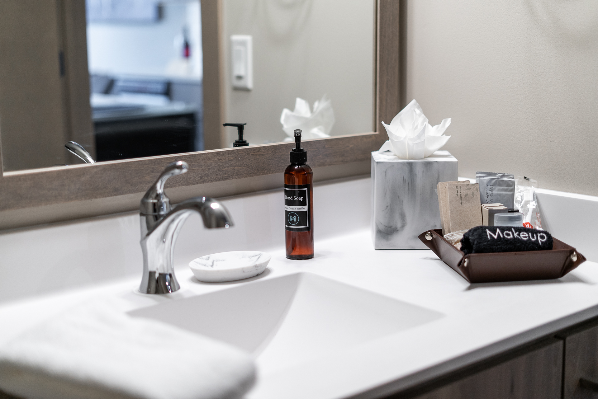 A modern bathroom vanity setup with hand soap, towels, and beauty products.