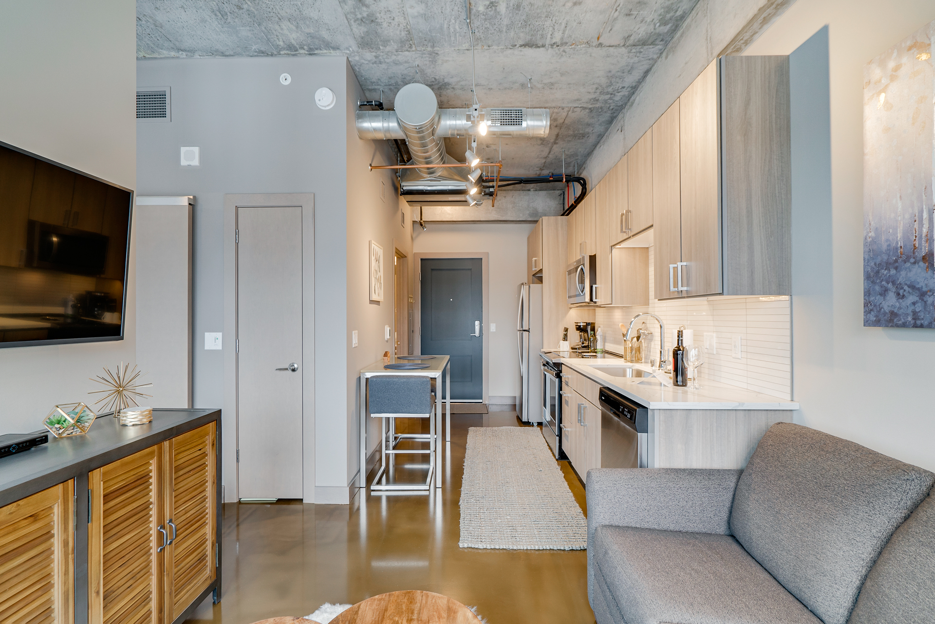 Modern industrial apartment interior with sleek kitchen and cozy seating area.
