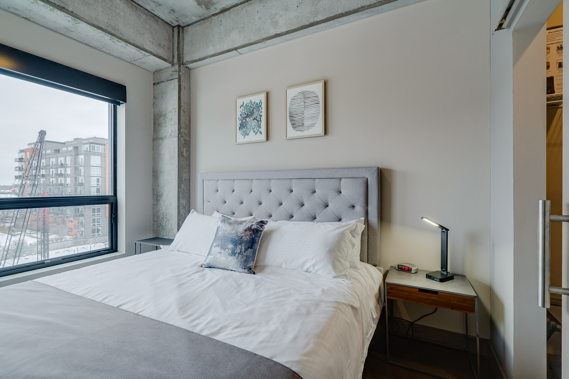 A stylish modern bedroom featuring a plush headboard and a view of an urban landscape.