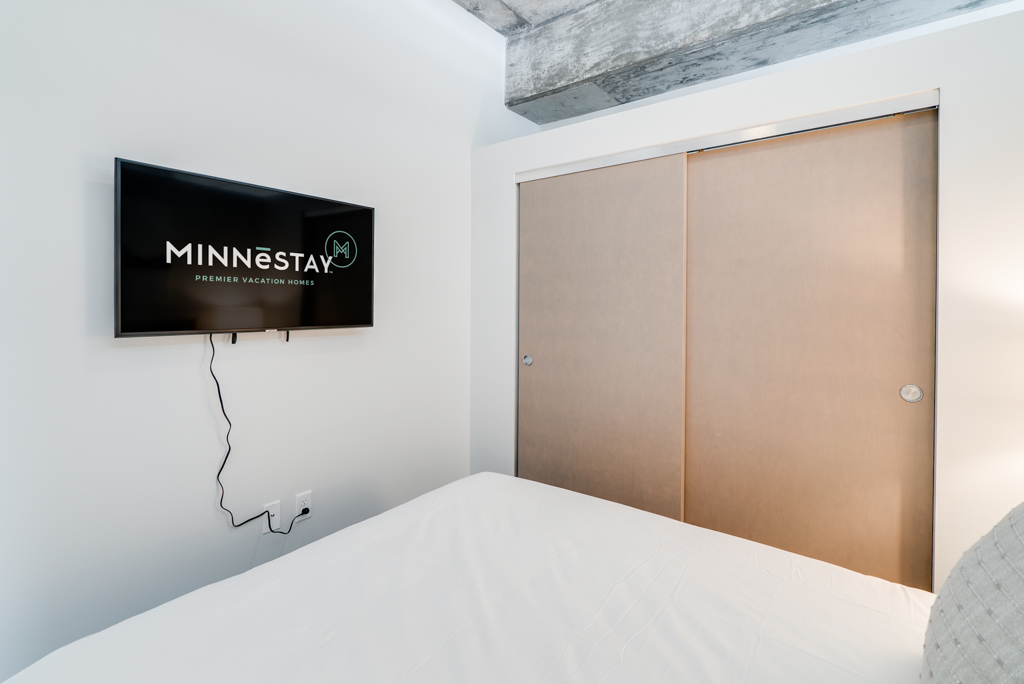 A stylish bedroom featuring a mounted TV and modern decor.