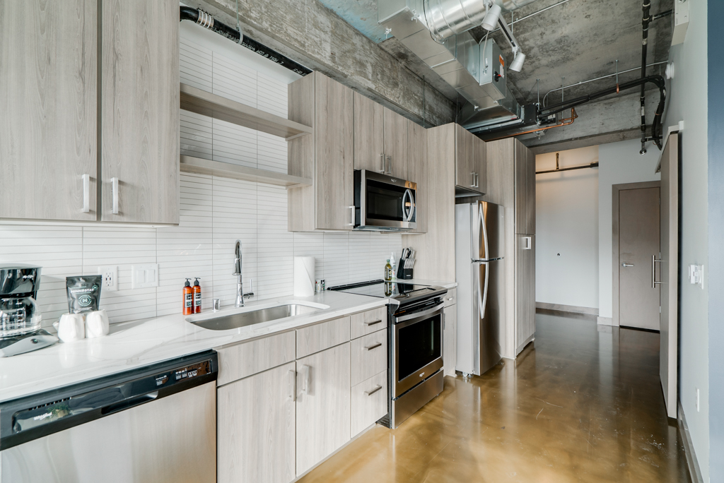 A modern, industrial-style kitchen featuring sleek wooden cabinets and stainless steel appliances.