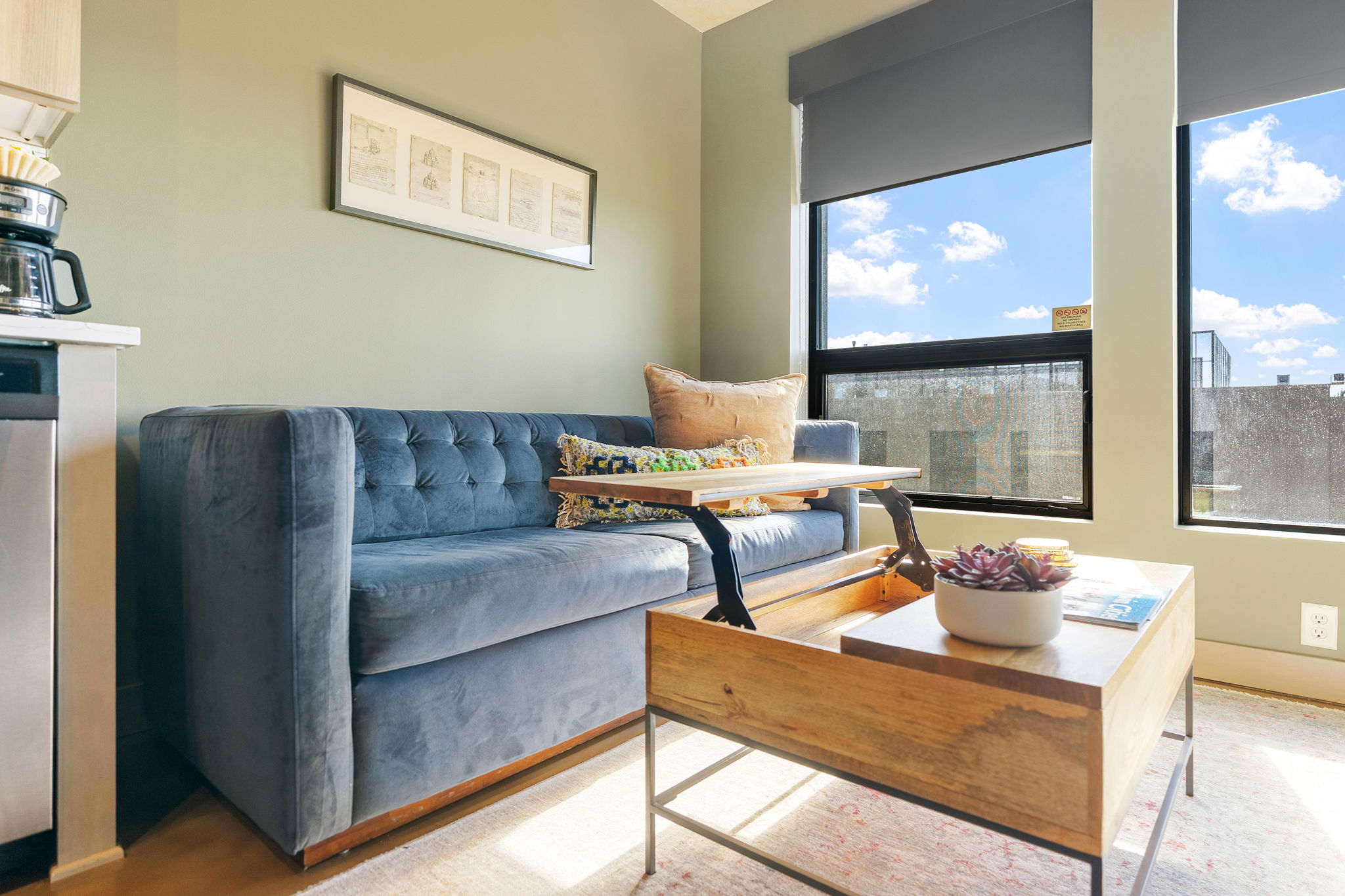 A cozy corner of a modern living space with a blue sofa and natural light from the windows.