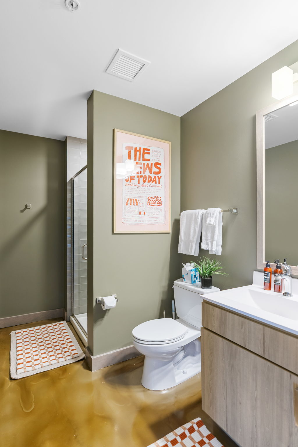 A stylish bathroom featuring olive green walls, modern fixtures, and vibrant decor.