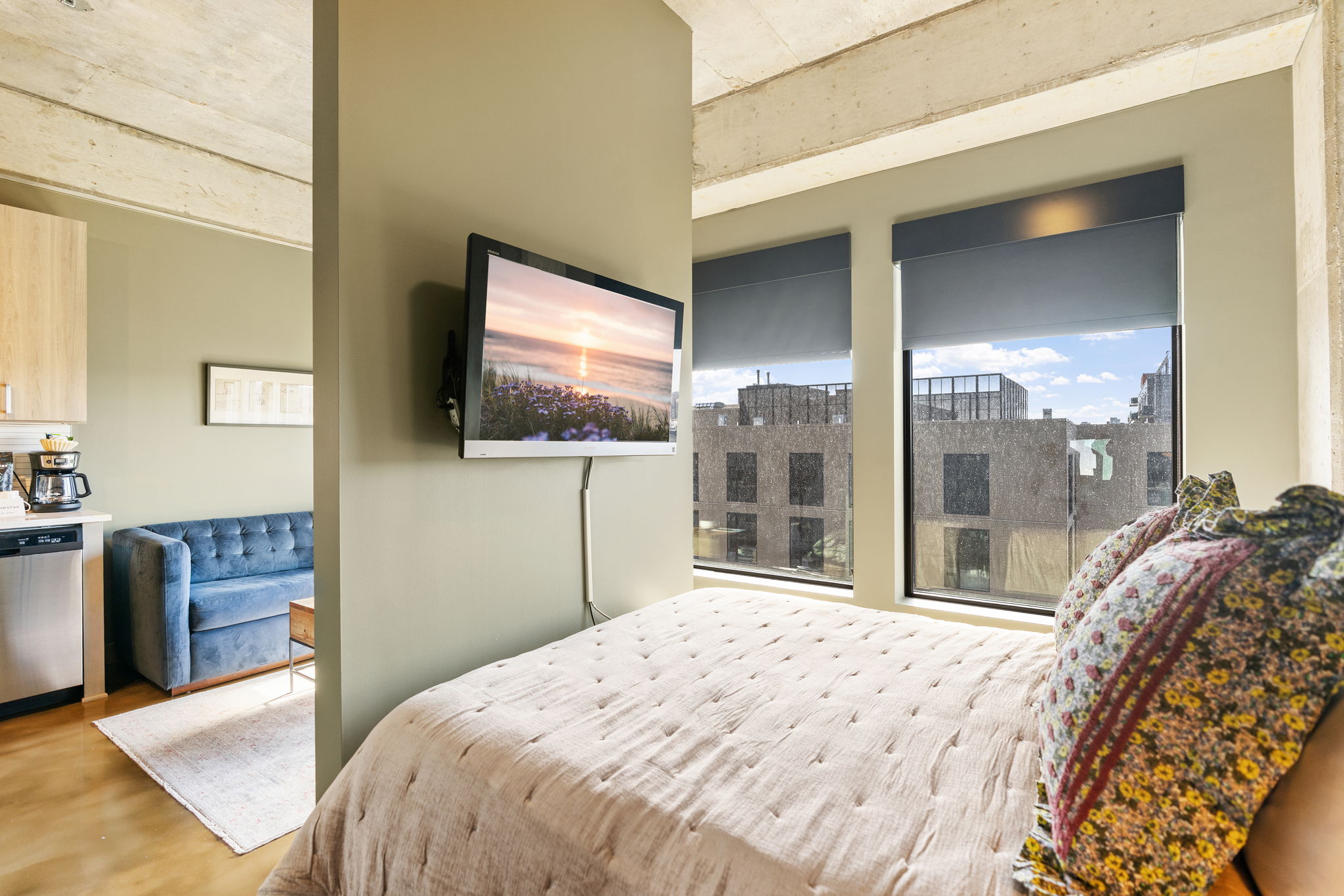 A modern studio apartment featuring a cozy sleeping area with large windows.