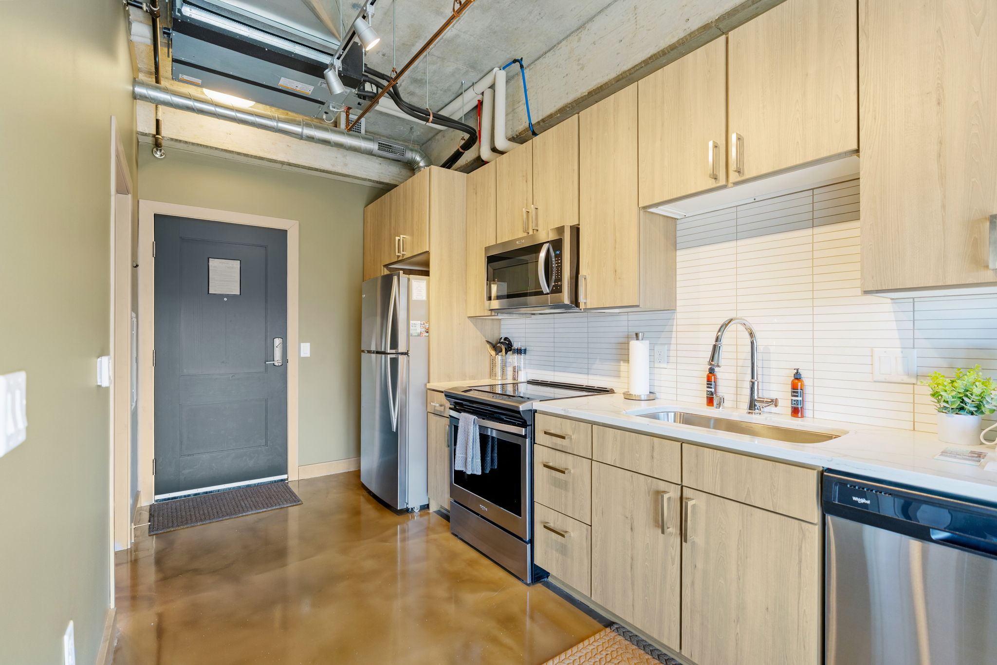 A modern kitchen with sleek cabinetry and stainless steel appliances in an apartment setting.