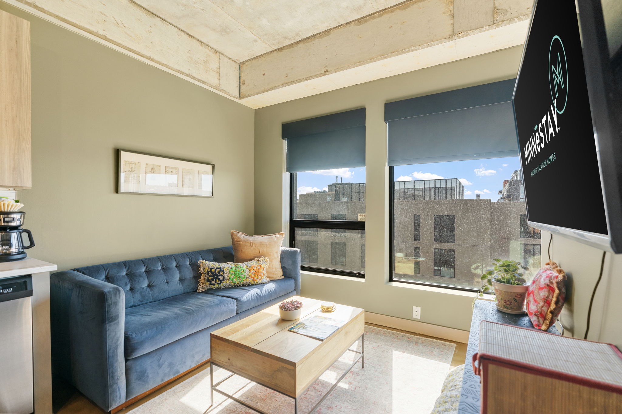 A stylish modern living room with a blue velvet couch and bright natural light.