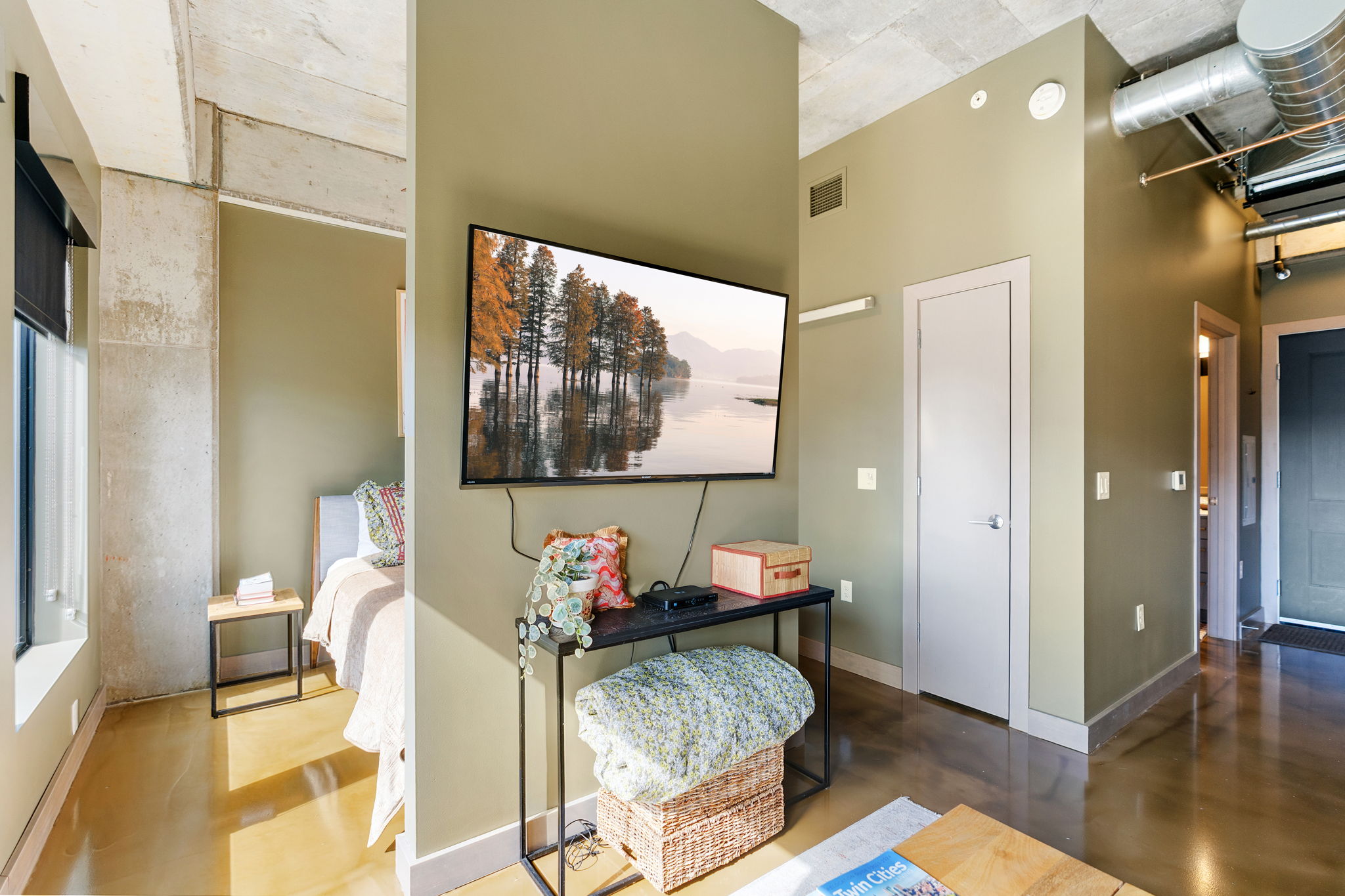 A modern living space featuring a serene landscape on the TV and cozy furnishings.