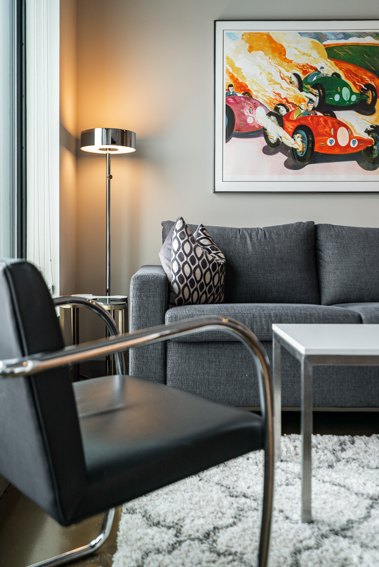 A modern living room featuring a stylish sofa, decorative pillows, and vibrant artwork of classic race cars.