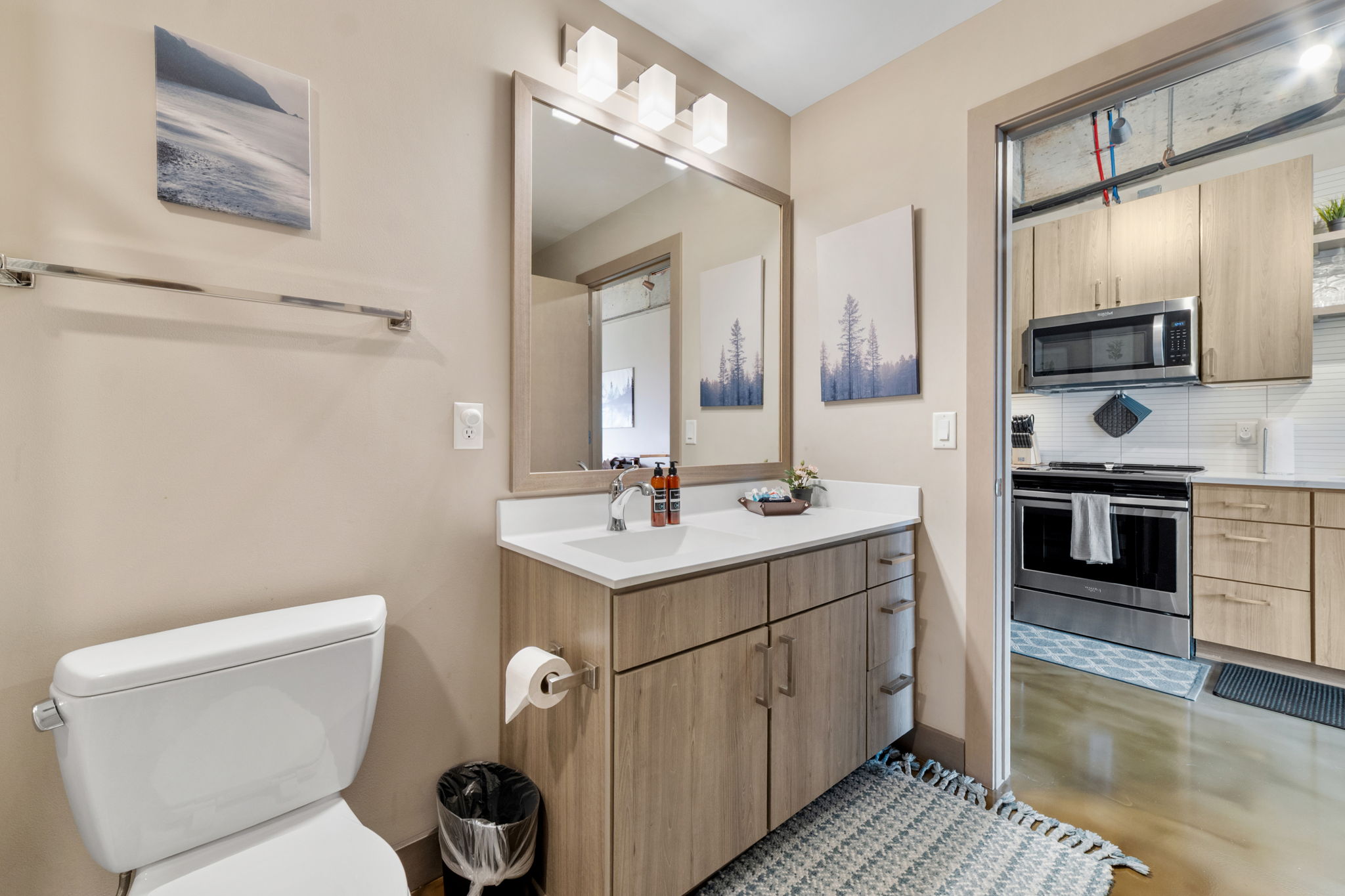 Modern bathroom with minimalist design and adjoining kitchen view.